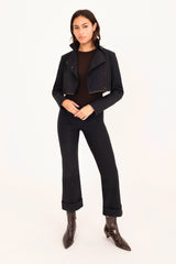 Person wearing a black jacket, black pants, and brown shoes on a white background