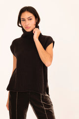 Woman wearing a brown sleeveless ribbed knit top against a white background