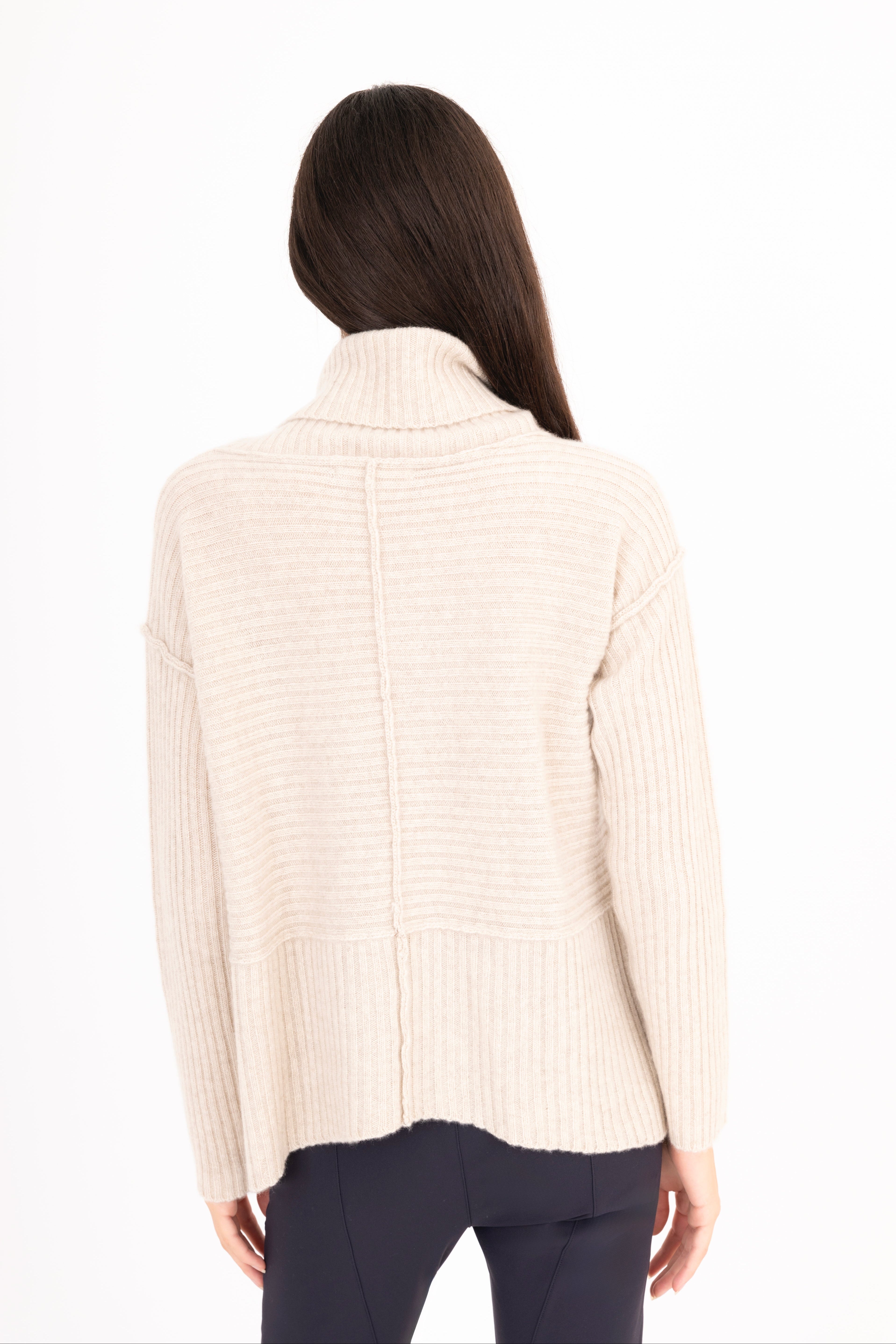 Woman wearing a beige ribbed sweater on a white background