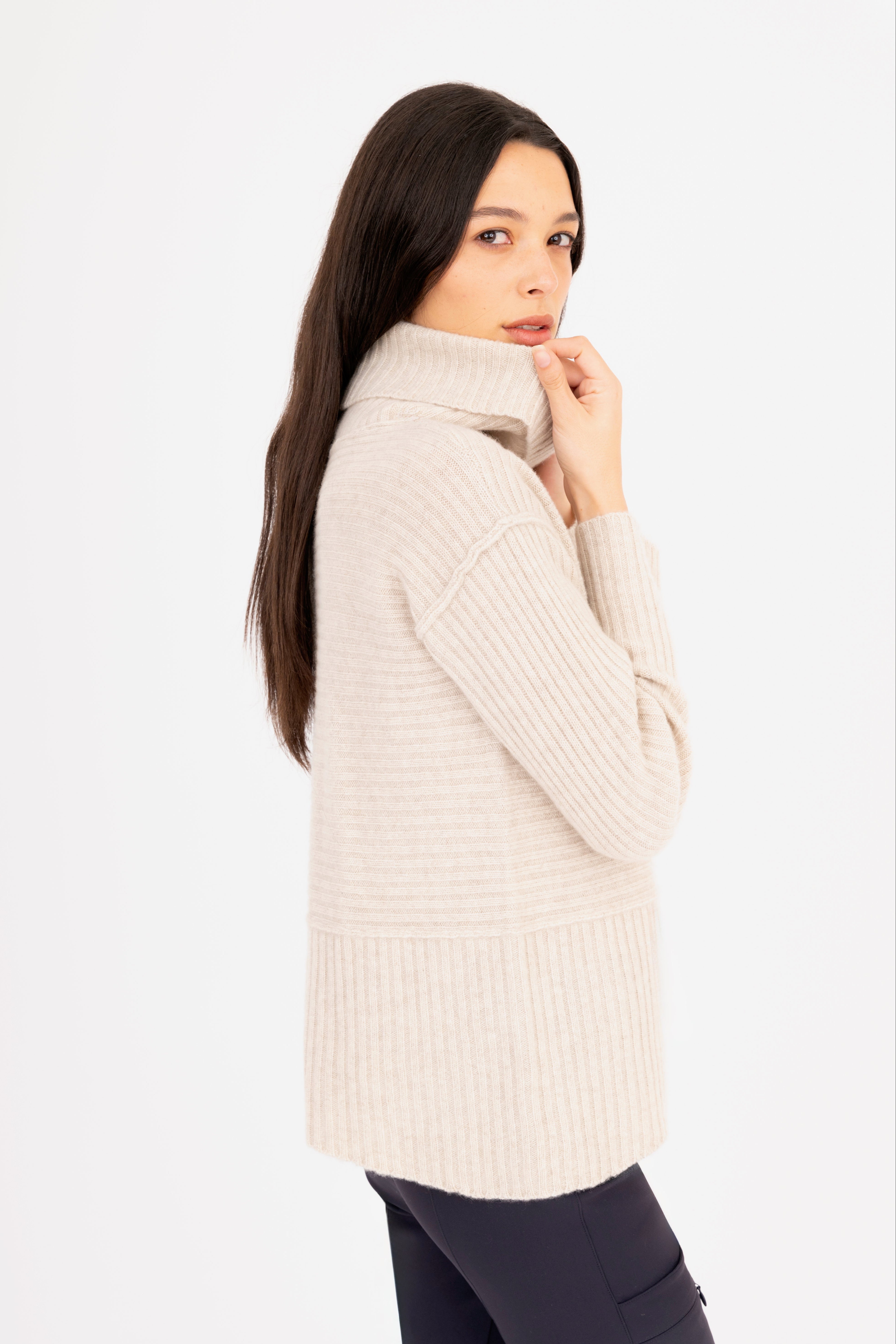 Woman wearing a beige ribbed sweater on a white background