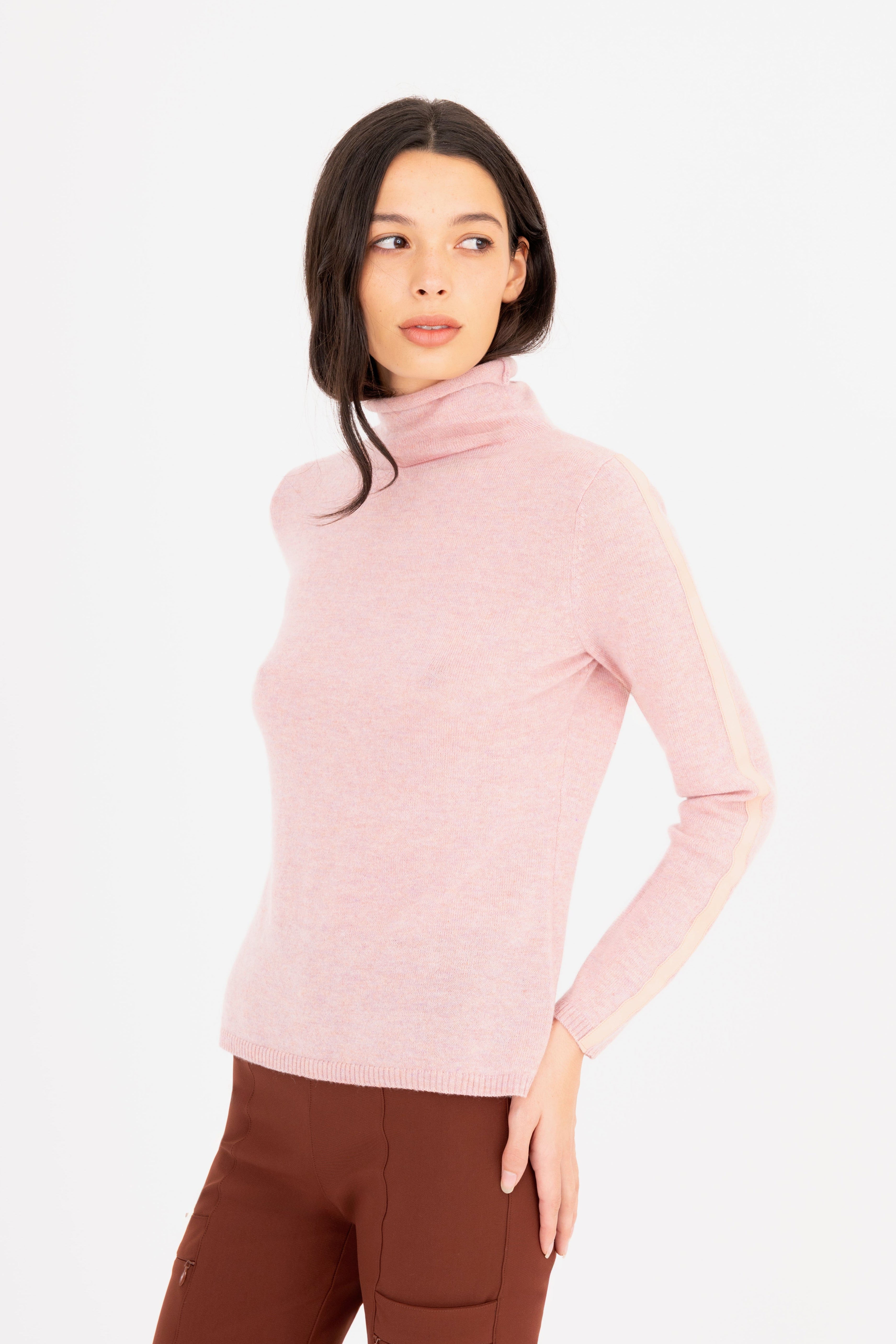 Woman wearing a light pink turtleneck sweater on a white 