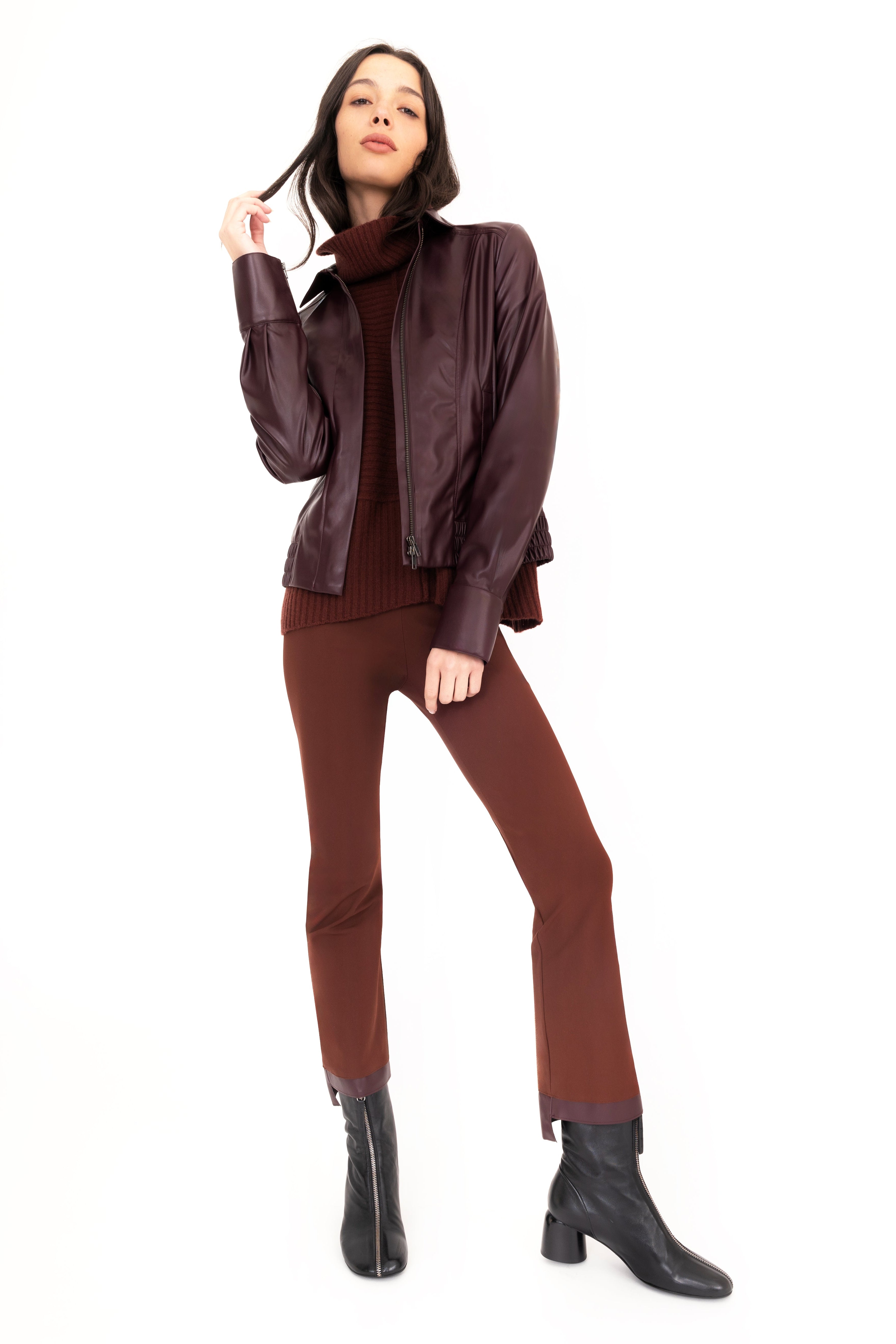 Woman wearing a brown jacket, pants, and boots on a white background