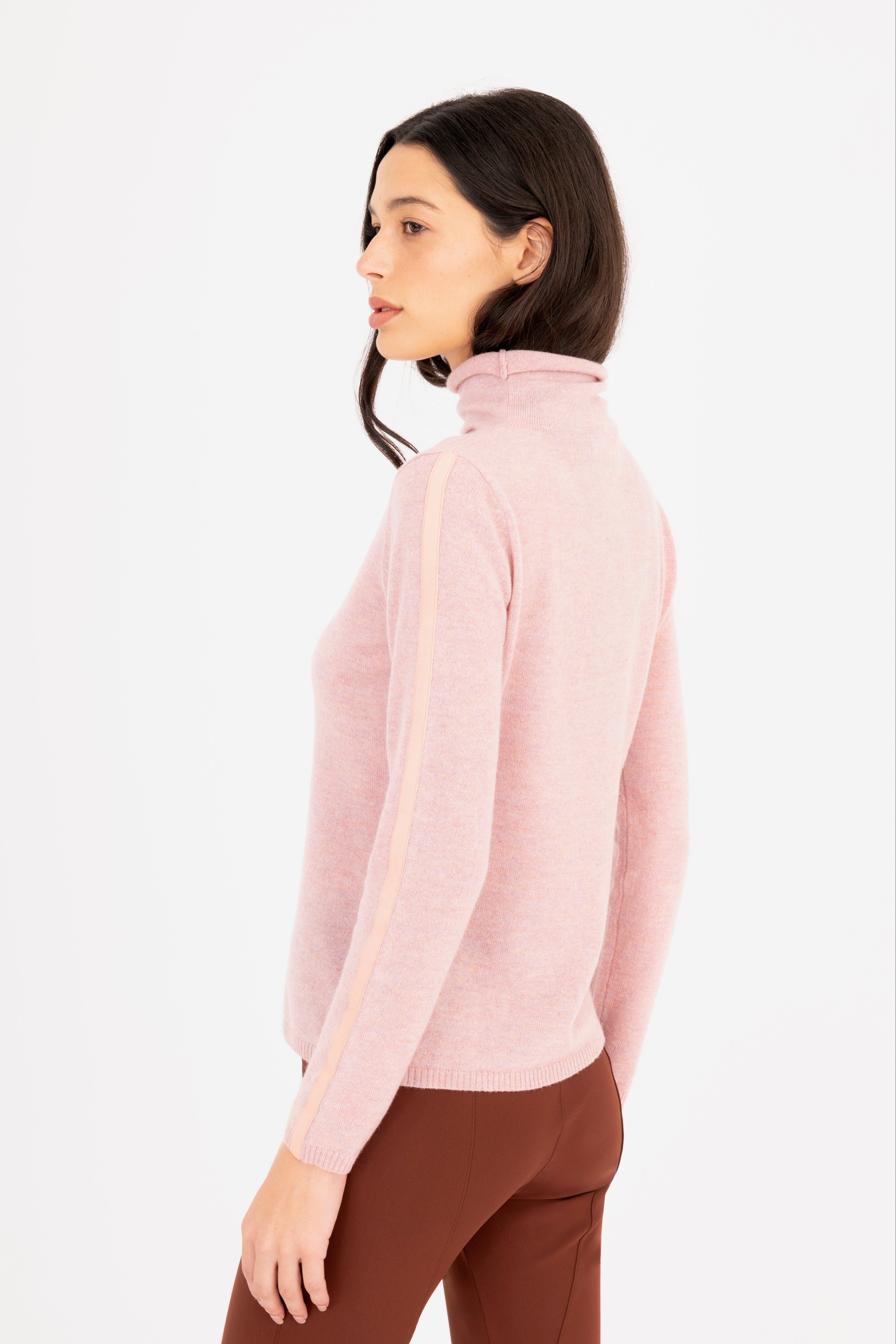 Woman wearing a light pink turtleneck sweater on a white 