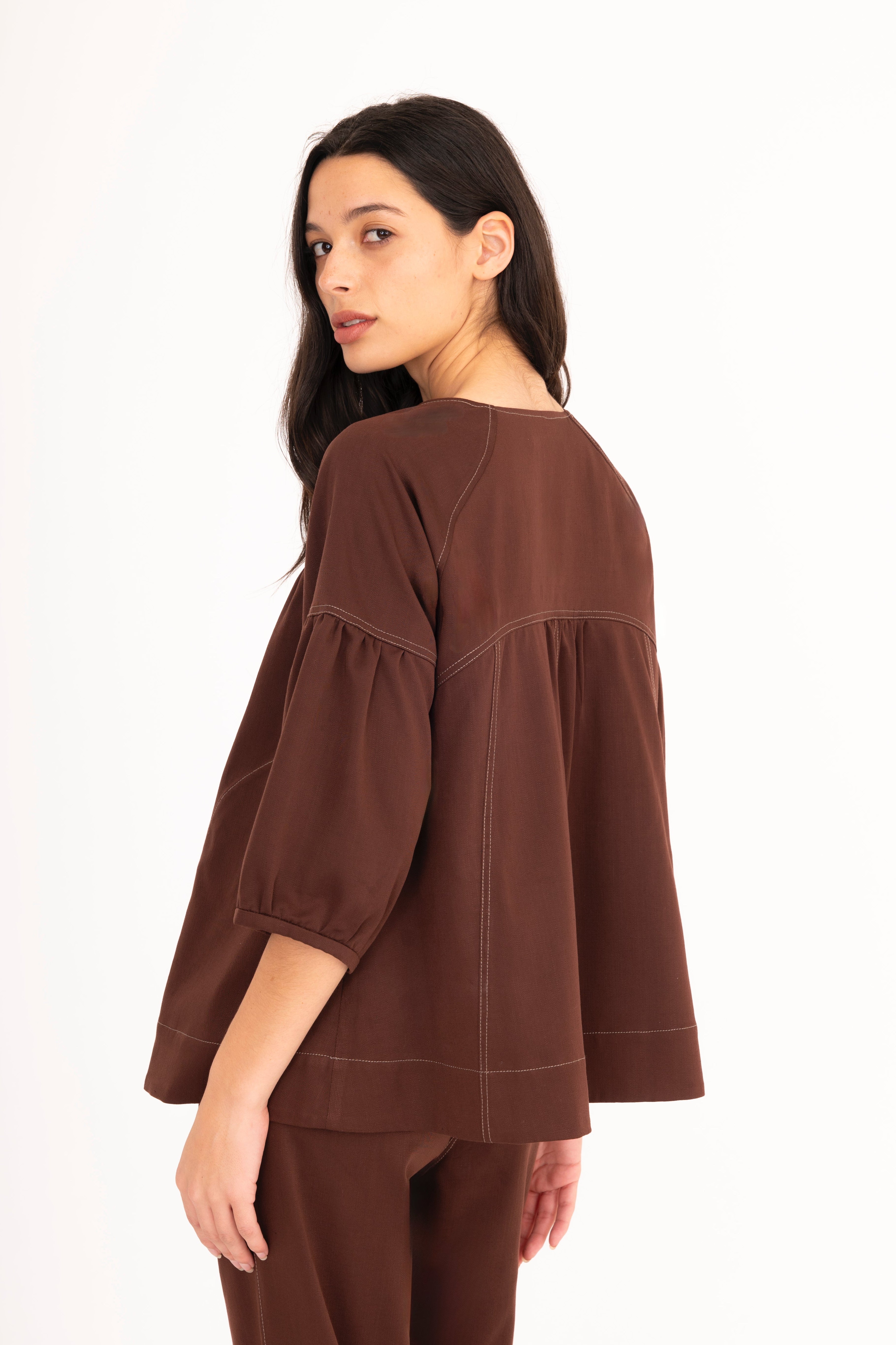 Woman wearing a brown blouse and pants on a white background