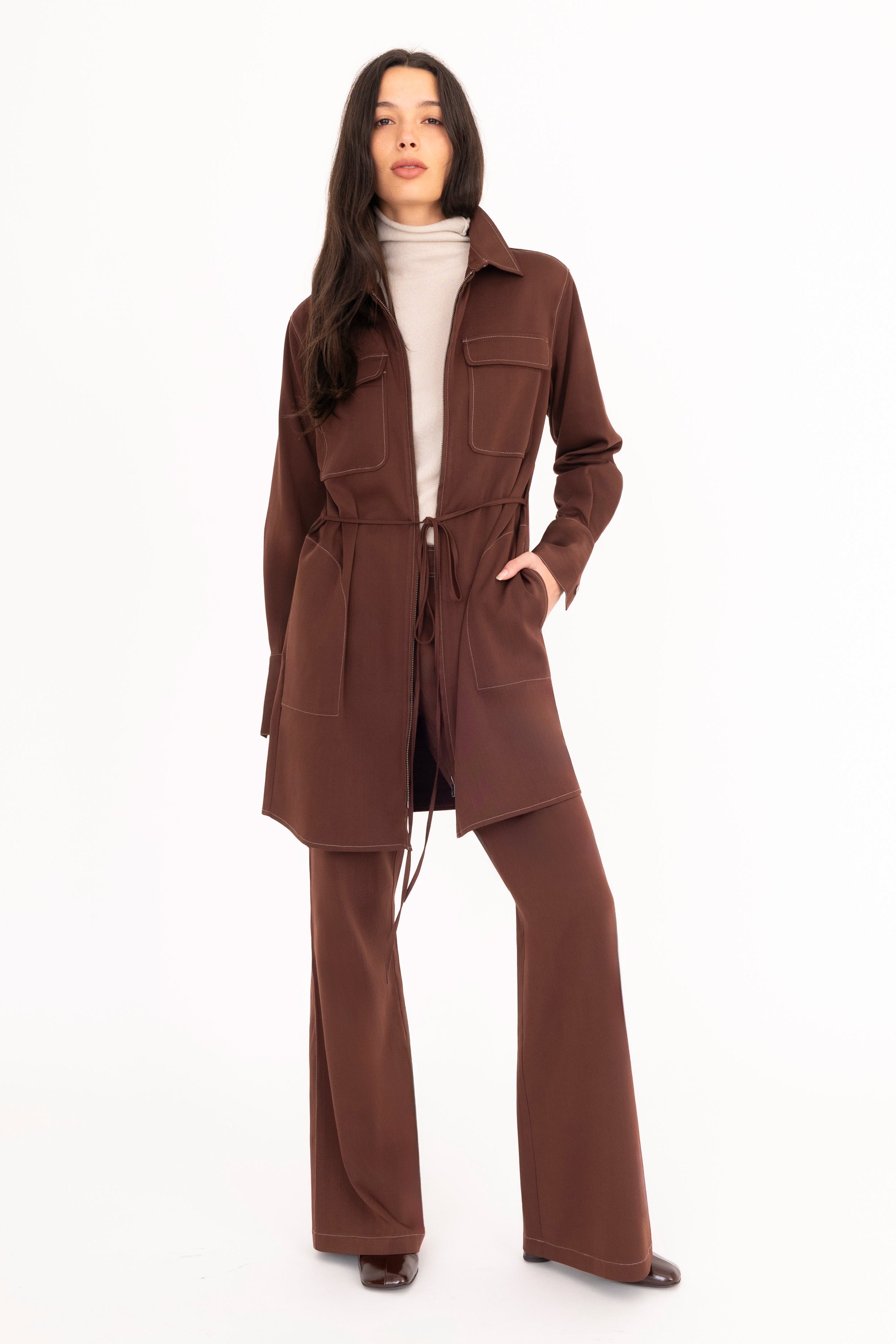 Woman wearing a brown coat and pants on a white background