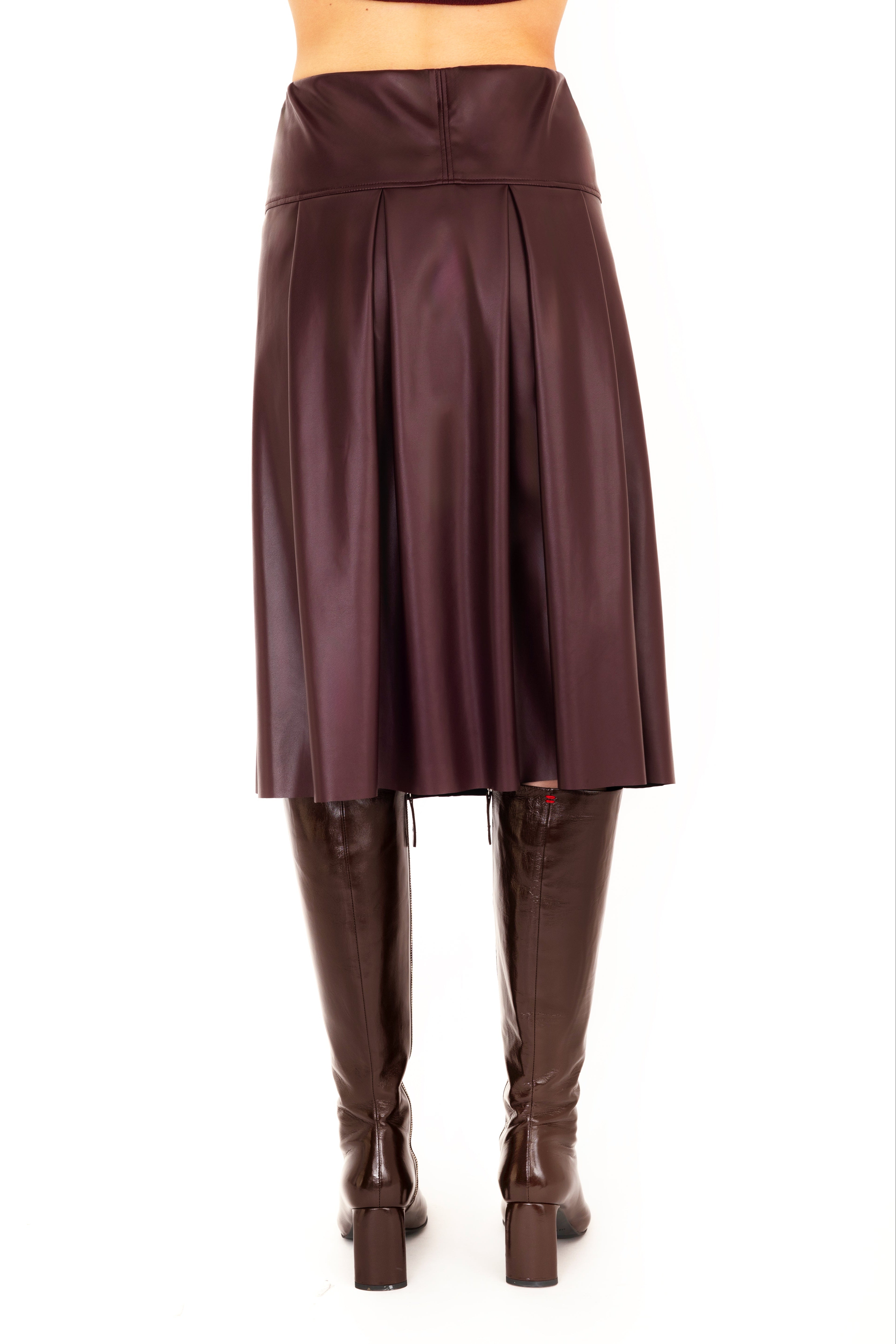 Person wearing a burgundy skirt and brown knee-high boots on a white 