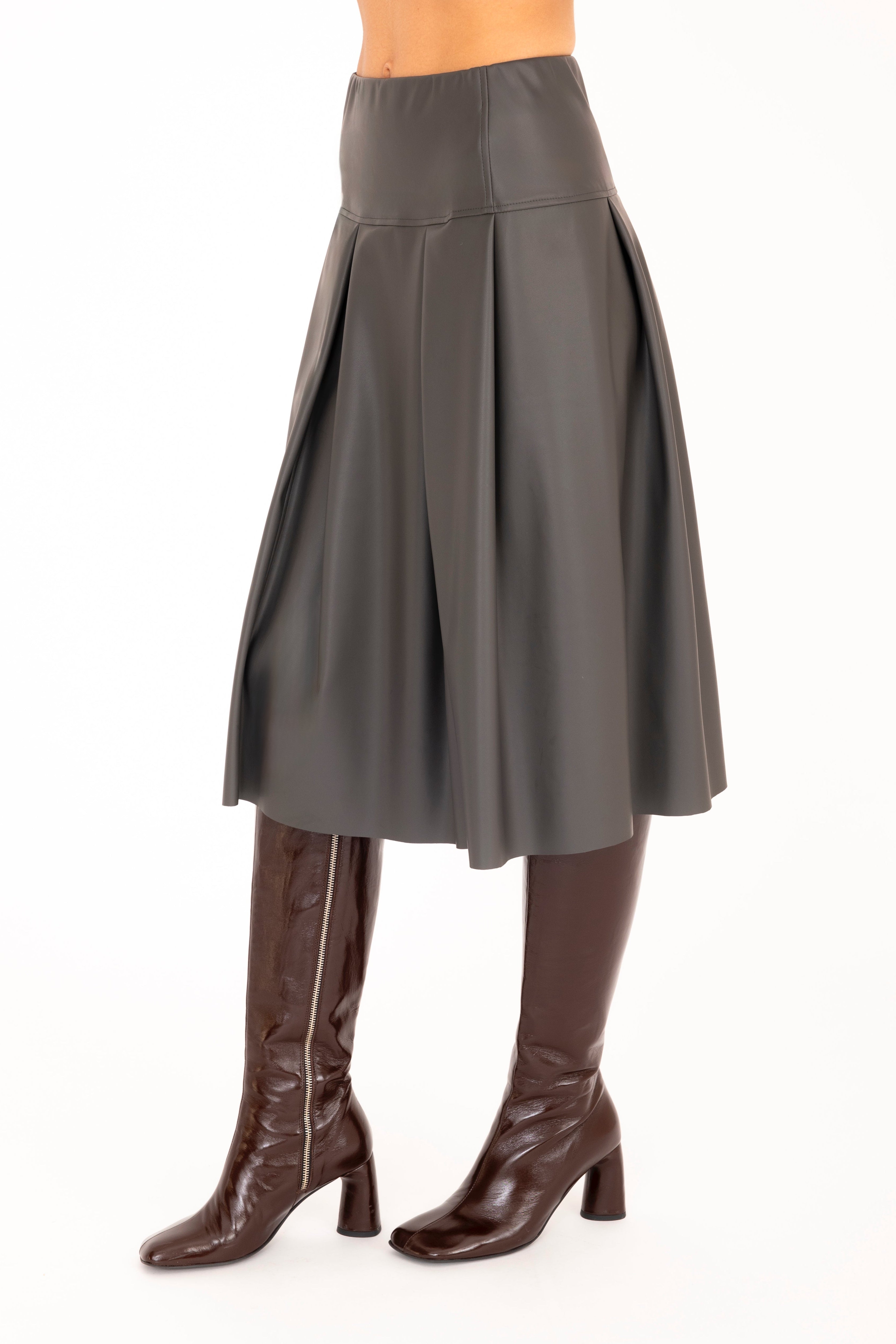 Person wearing a gray skirt and brown knee-high boots on a white background
