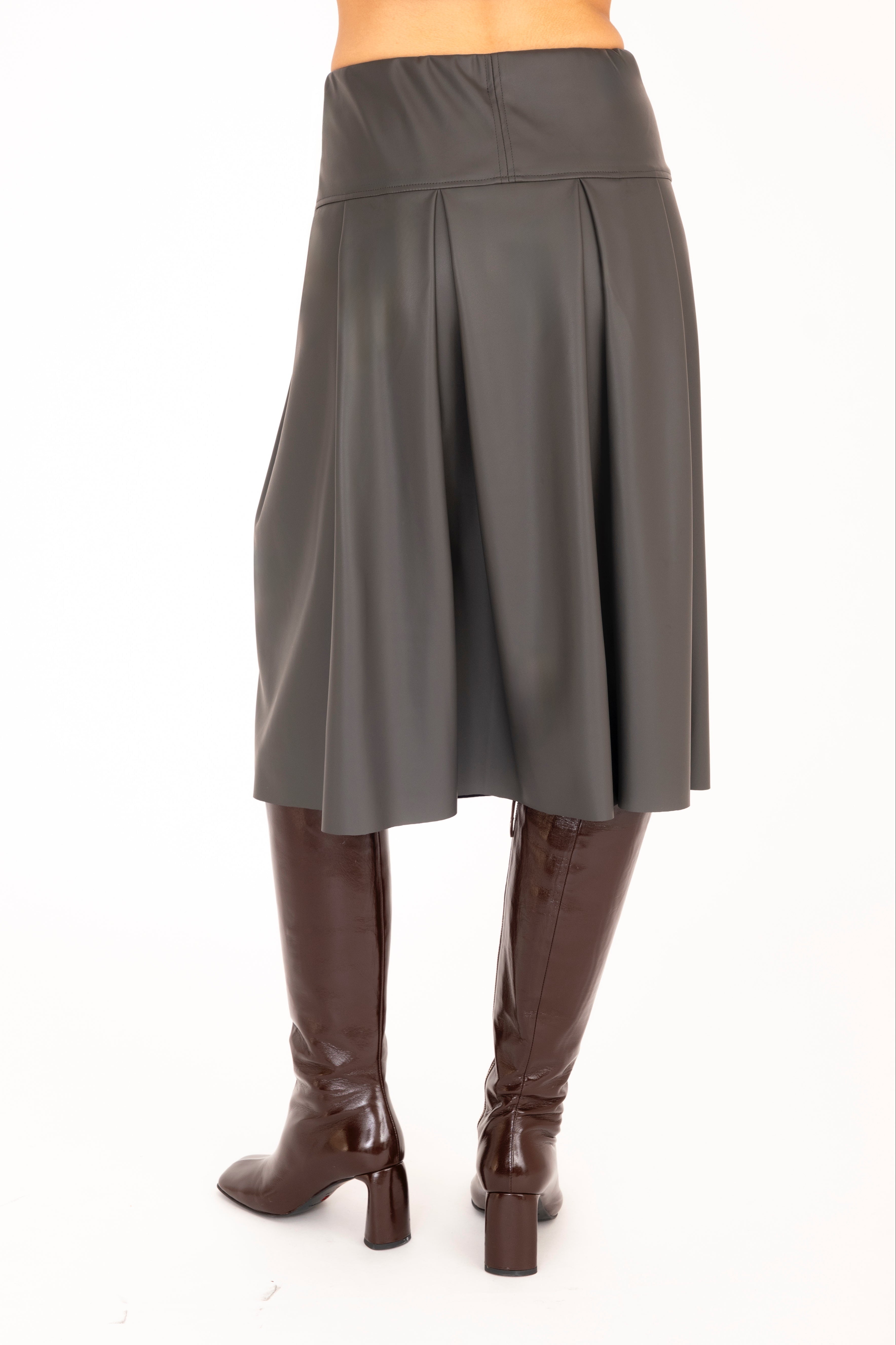 Person wearing a gray skirt and brown knee-high boots on a white background
