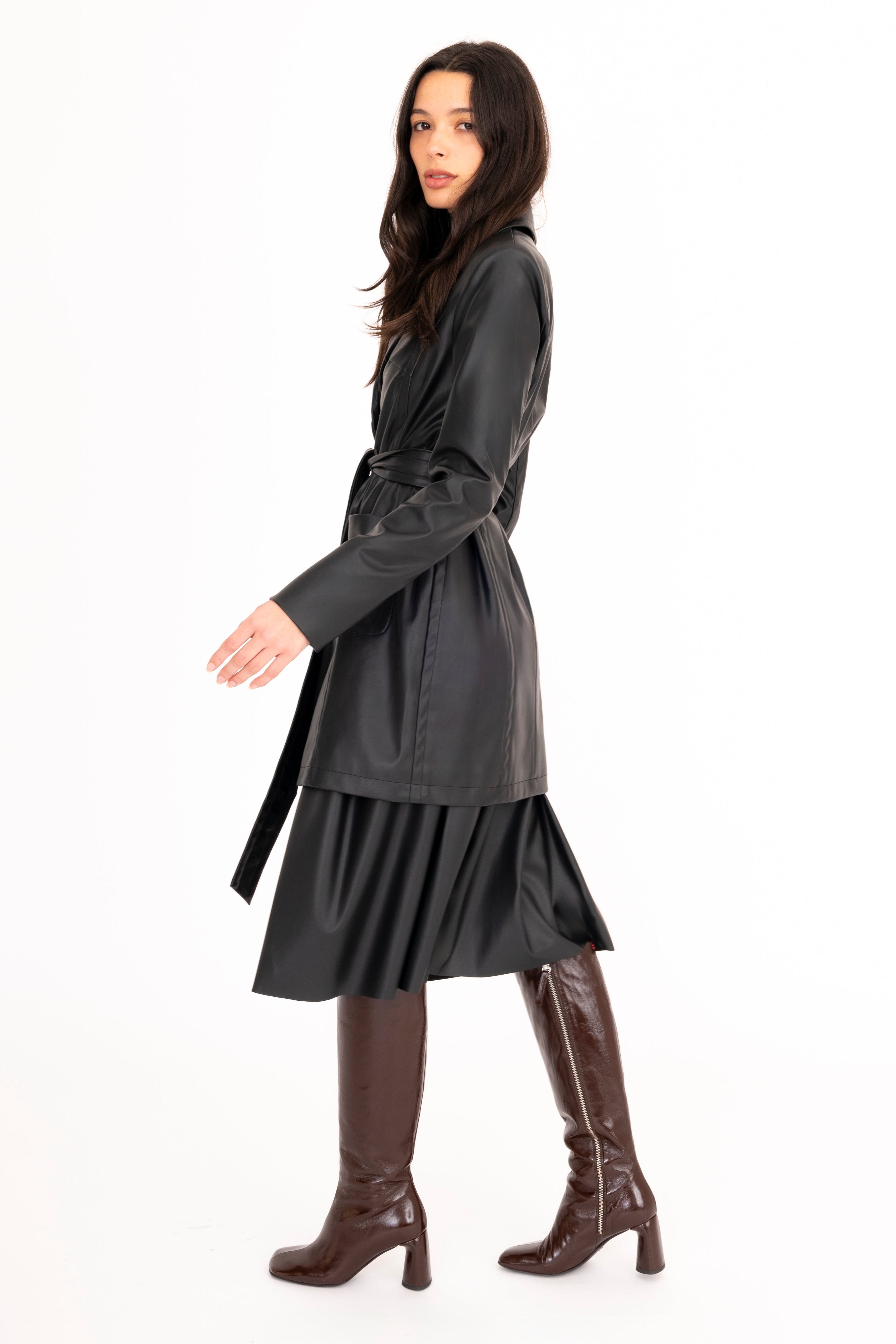 Woman wearing a gray coat and brown boots on a white background