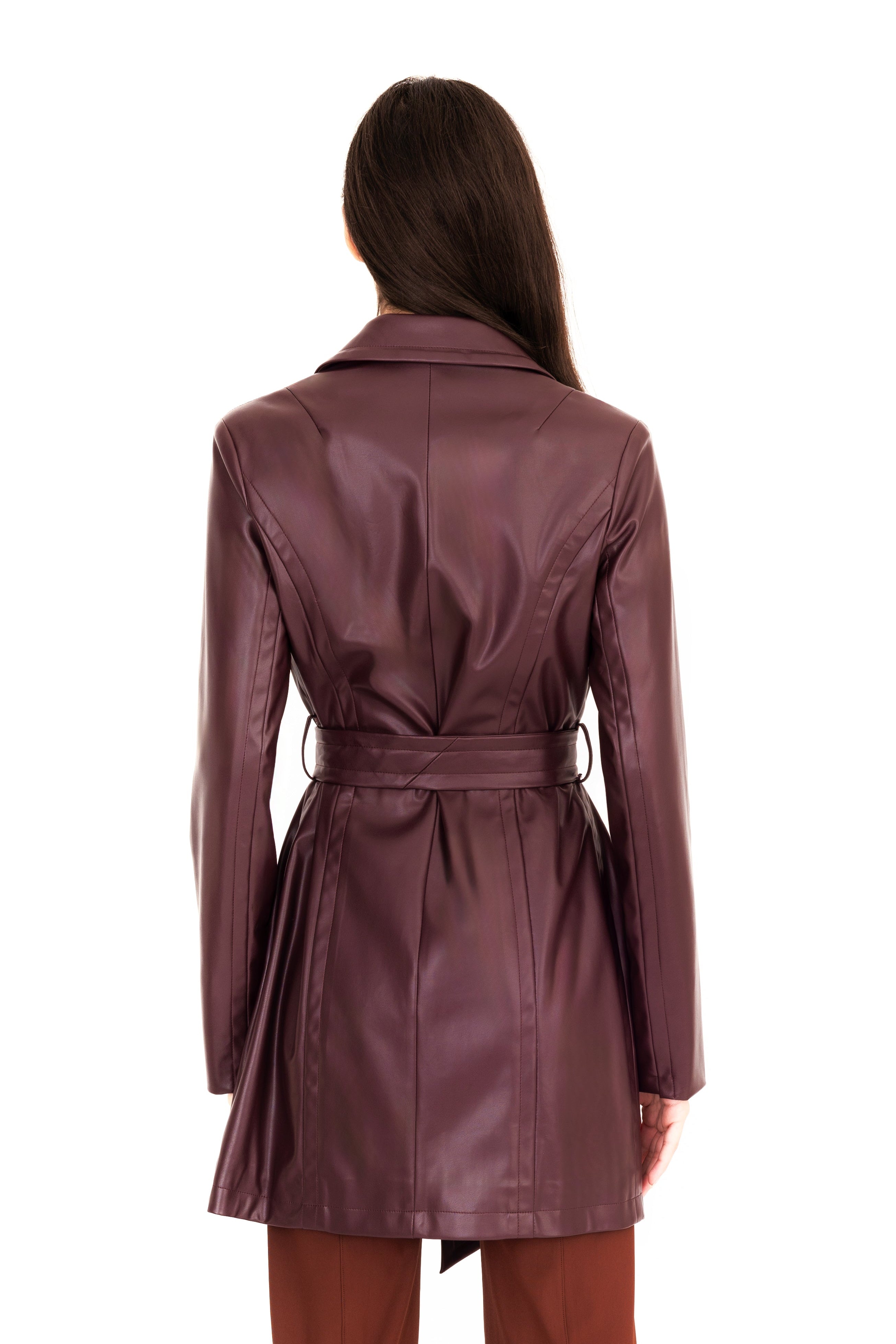 Woman wearing a burgundy trench coat and pants on a white 
