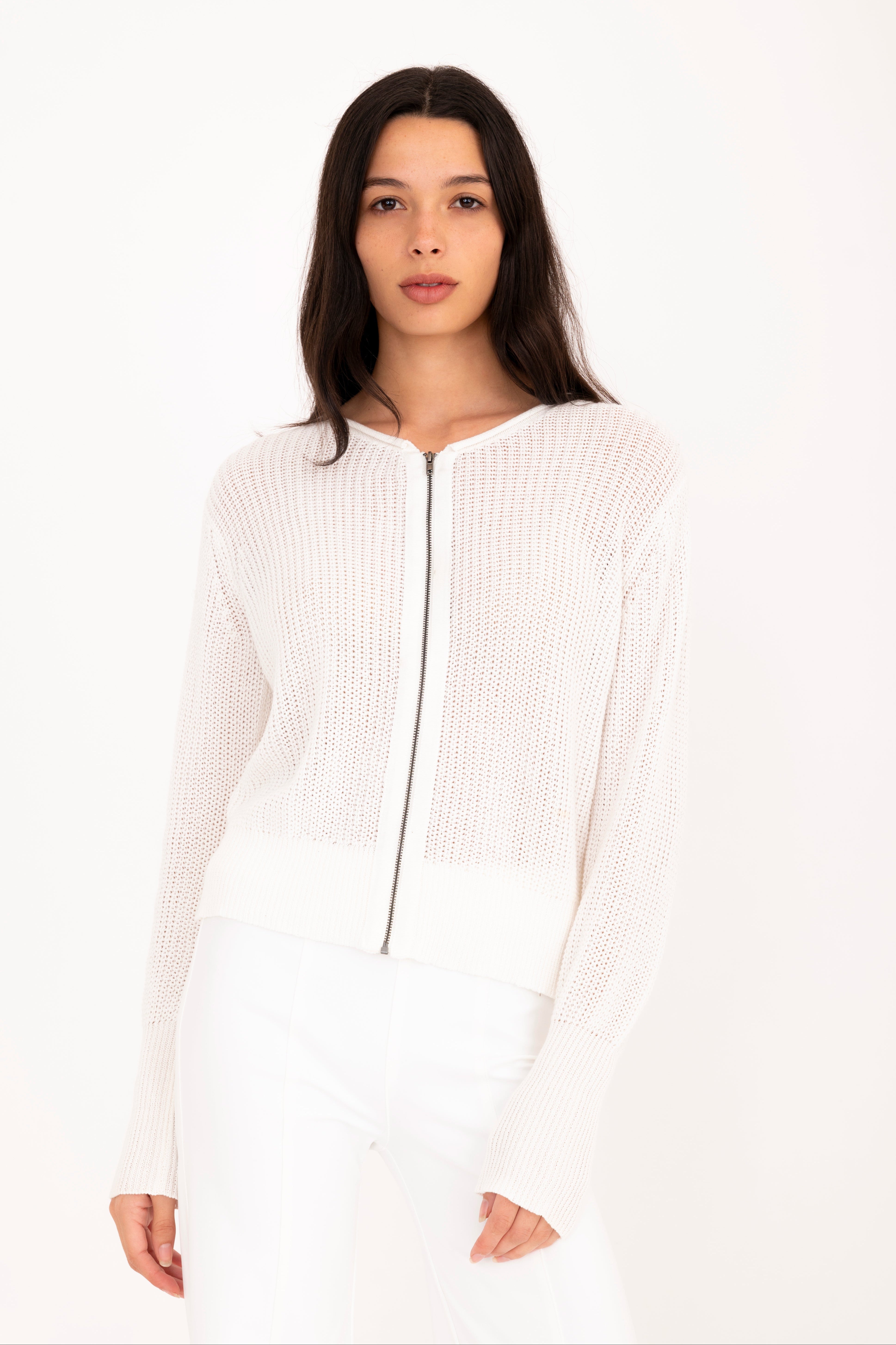 Woman wearing a white zip-up sweater against a white background