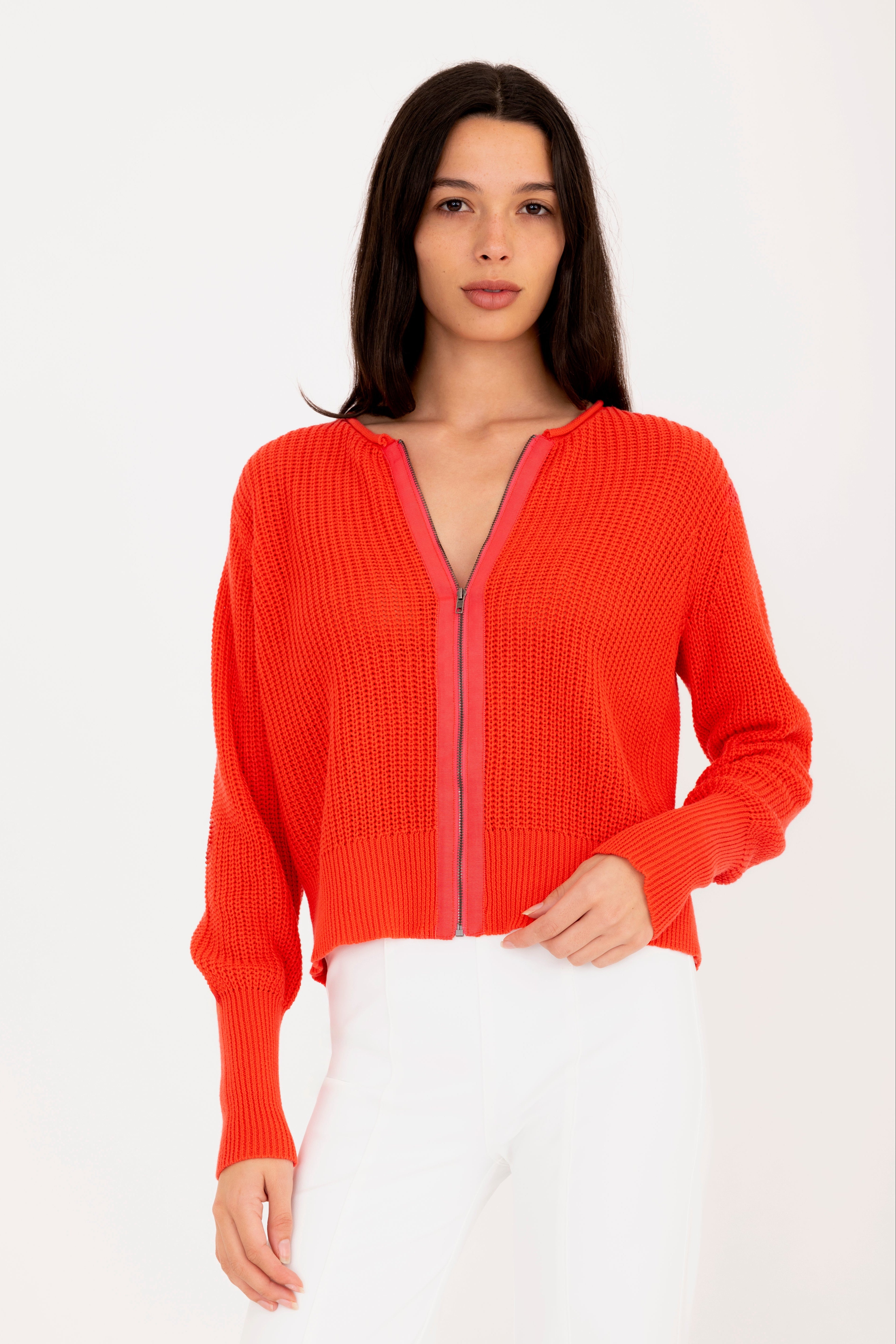 Woman wearing a orange zip-up sweater against a white background