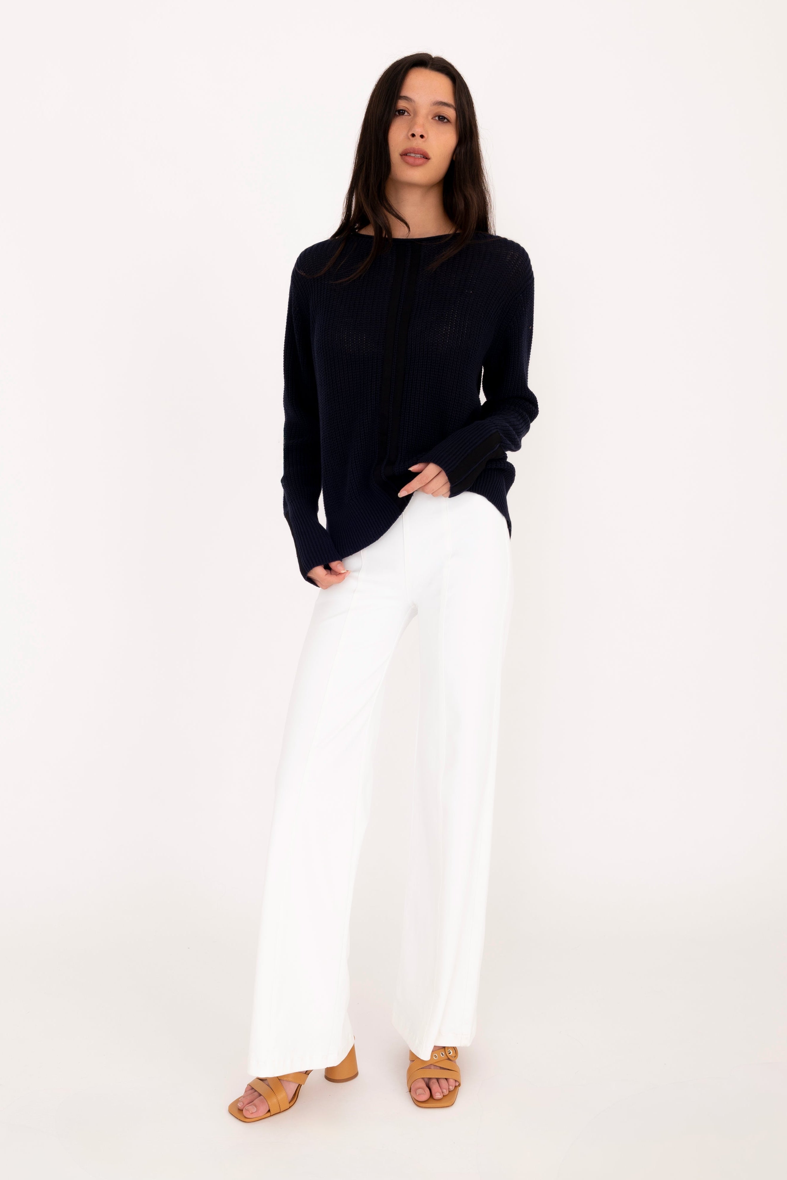 Person wearing a black sweater and white pants on a white background