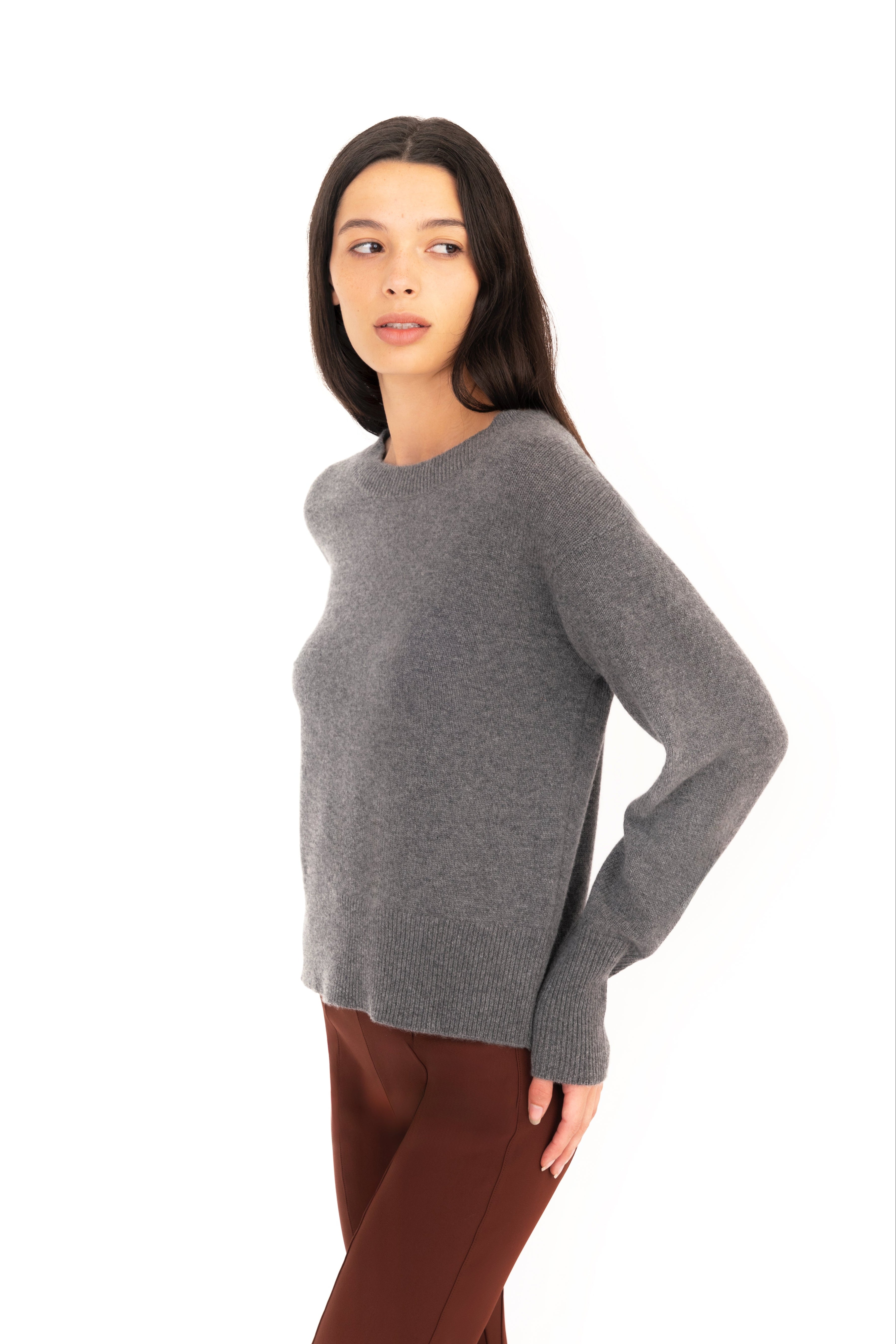 Woman wearing a gray sweater and brown pants on a white background