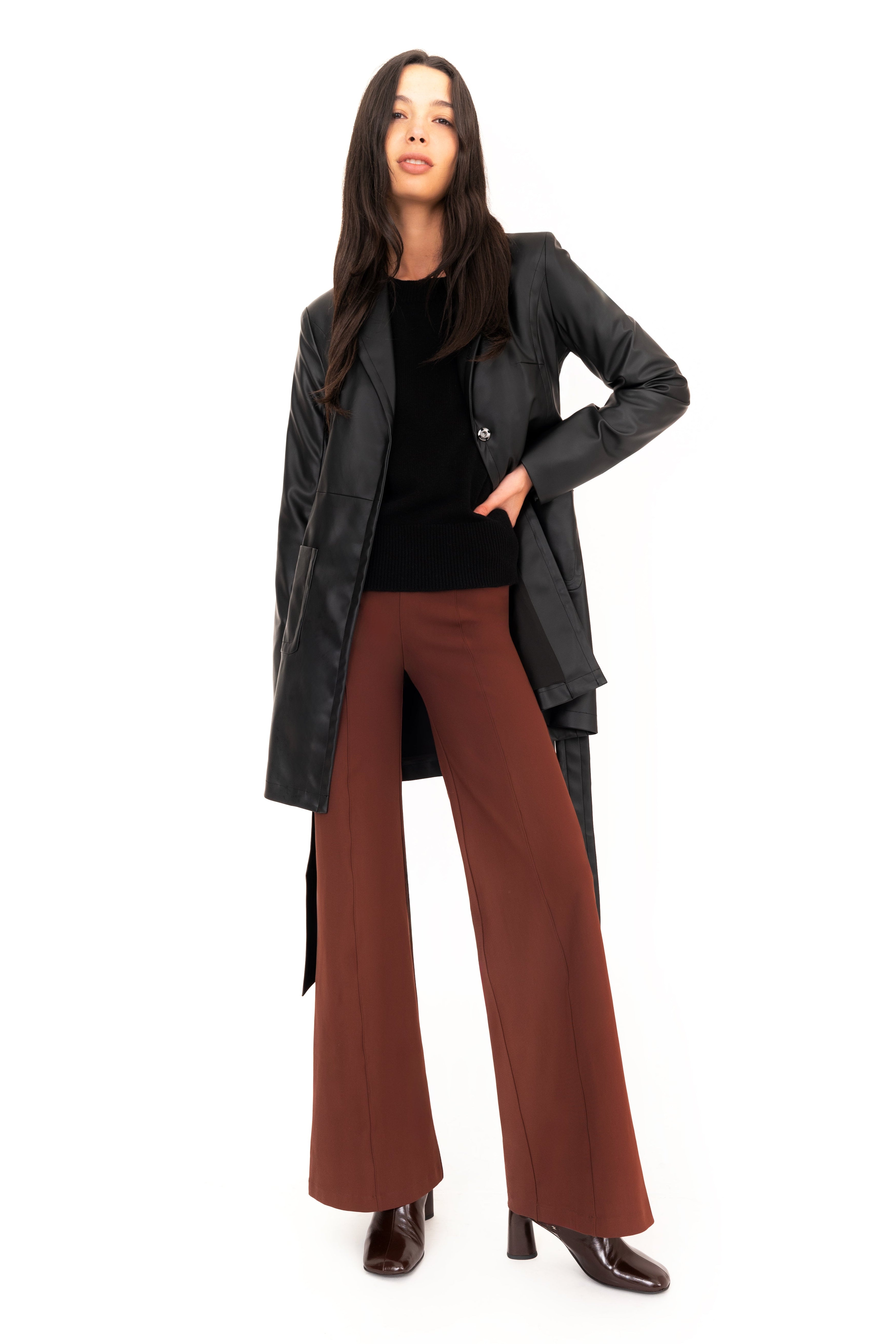 Woman wearing a black coat and brown pants on a white background