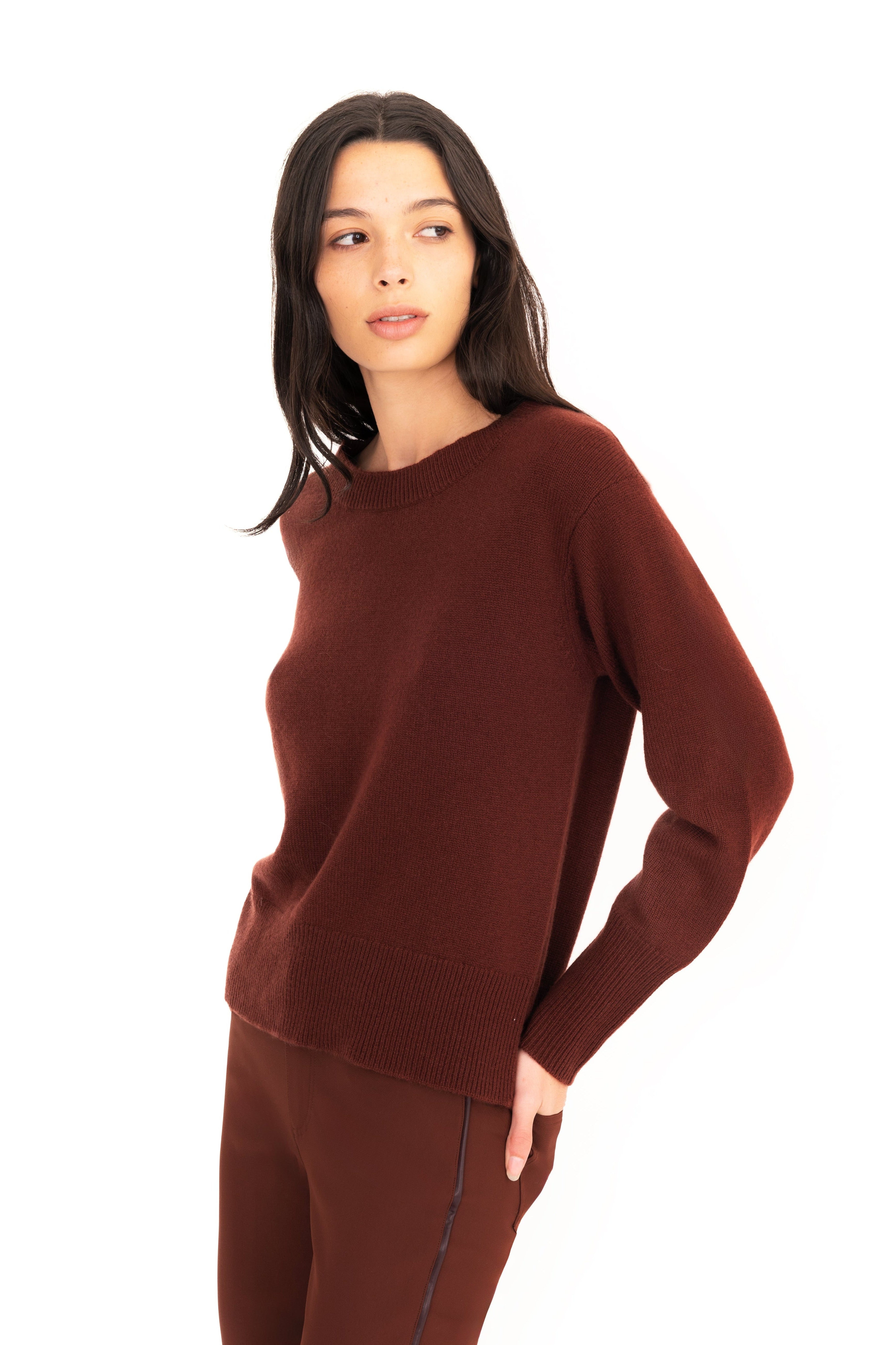 Woman wearing a brown sweater and pants on a white background
