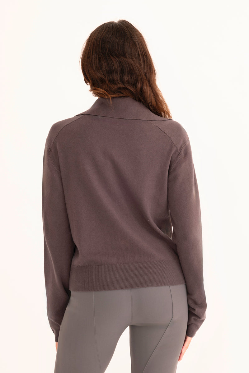 Woman wearing a dark grey moto sweater on a white background