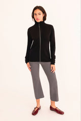 Woman wearing a black zip-up jacket and gray pants on a white background