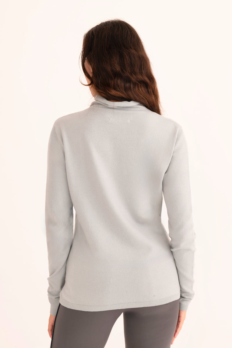 Woman wearing a light blue turtleneck sweater on a white background