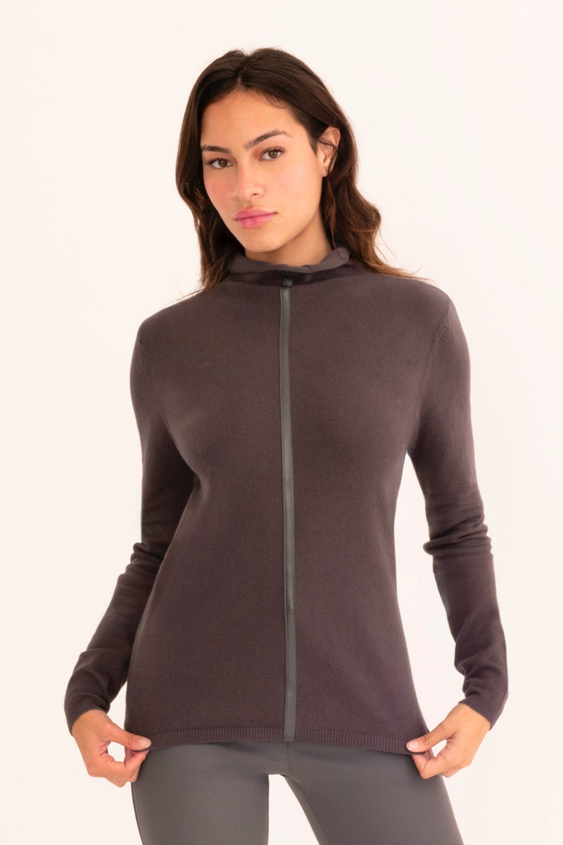 Woman wearing a dark grey turtleneck sweater on a white background