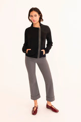 Woman wearing a black jacket, gray pants, and red shoes on a white background