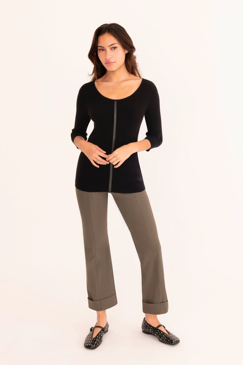 Woman wearing a black top and gray pants on a white background