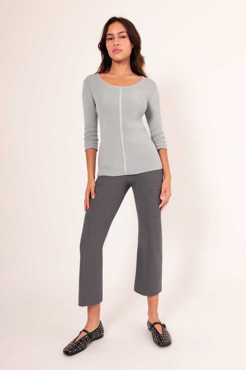 Woman wearing a gray long-sleeve top and gray pants on a white background