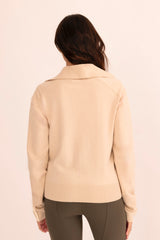 Woman wearing a light beige moto sweater on a white background