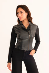 Woman wearing a black leather jacket and black pants on a white background