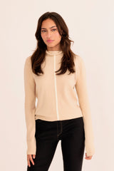 Woman wearing a light beige turtleneck sweater on a white background