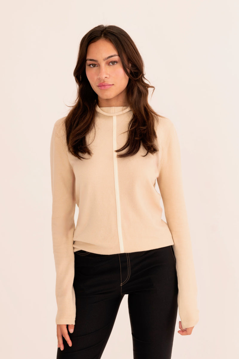 Woman wearing a light beige turtleneck sweater on a white background