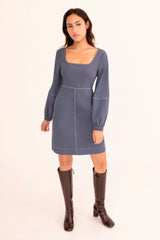 Woman wearing a blue dress with brown boots on a white background