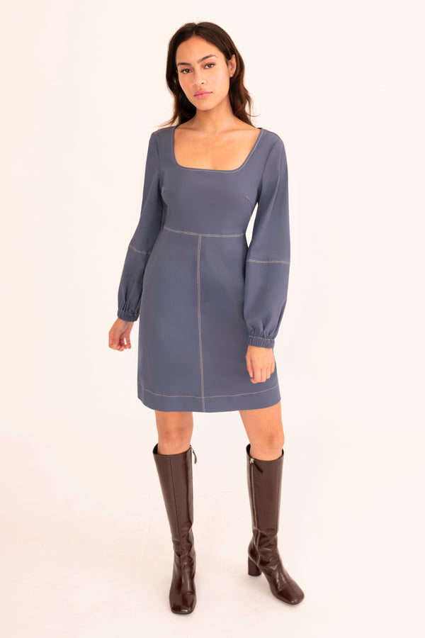 Woman wearing a blue dress with brown boots on a white background