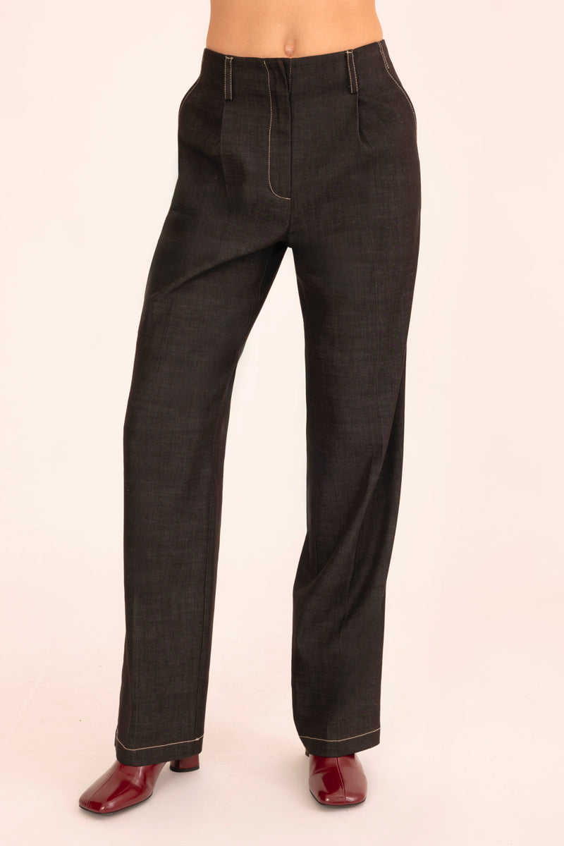 Black pants worn by a person on a beige background