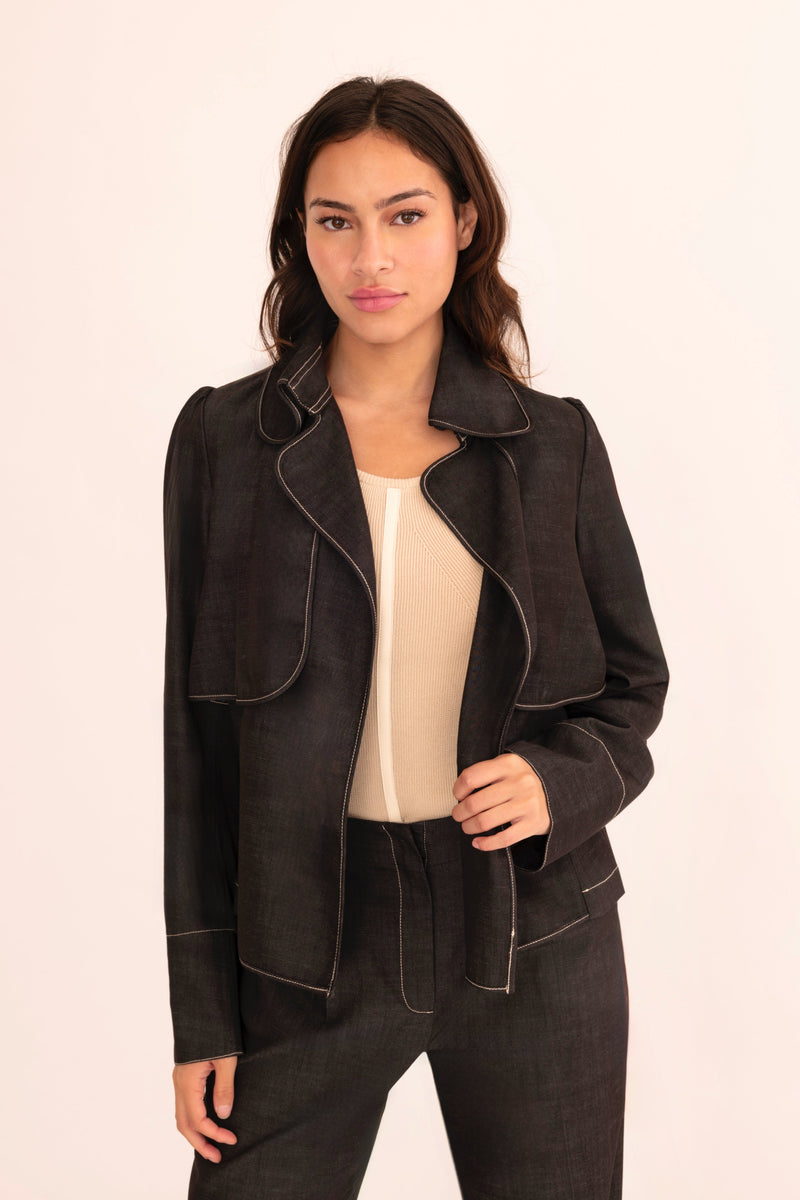 Woman wearing a black jacket and pants on a beige background