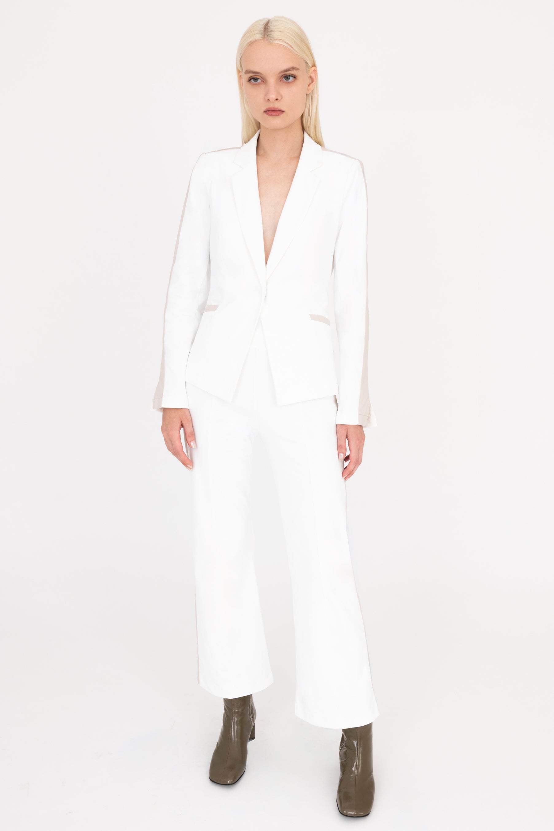 Woman wearing a white suit with beige side stripe on a white background
