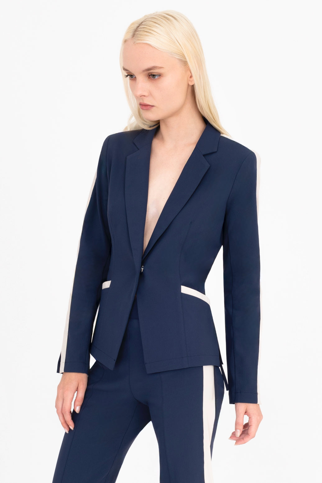 Woman wearing a indigo blue  suit with beige side stripe on a white background