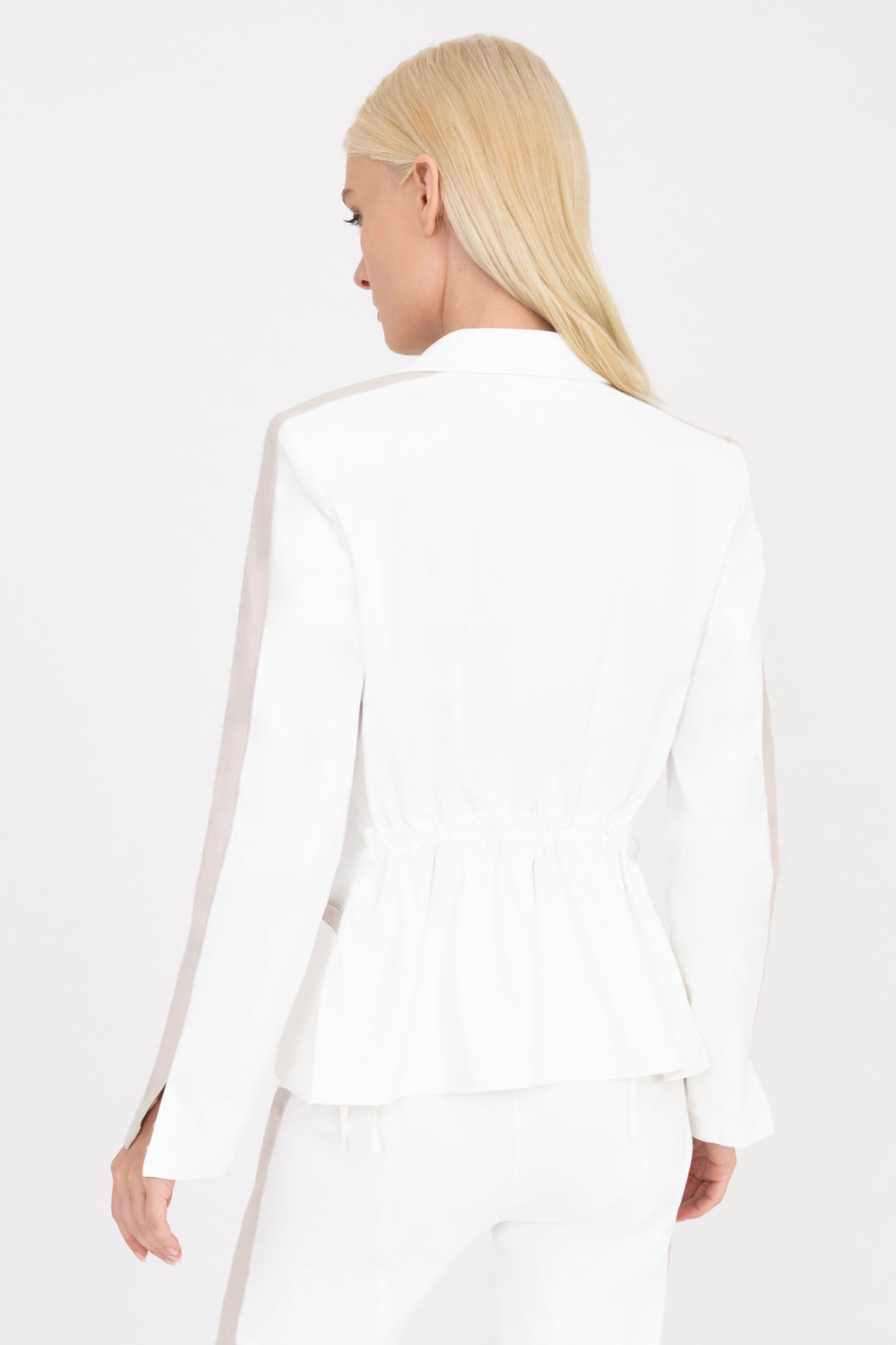 Woman wearing a white blazer with beige side stripe on a white background