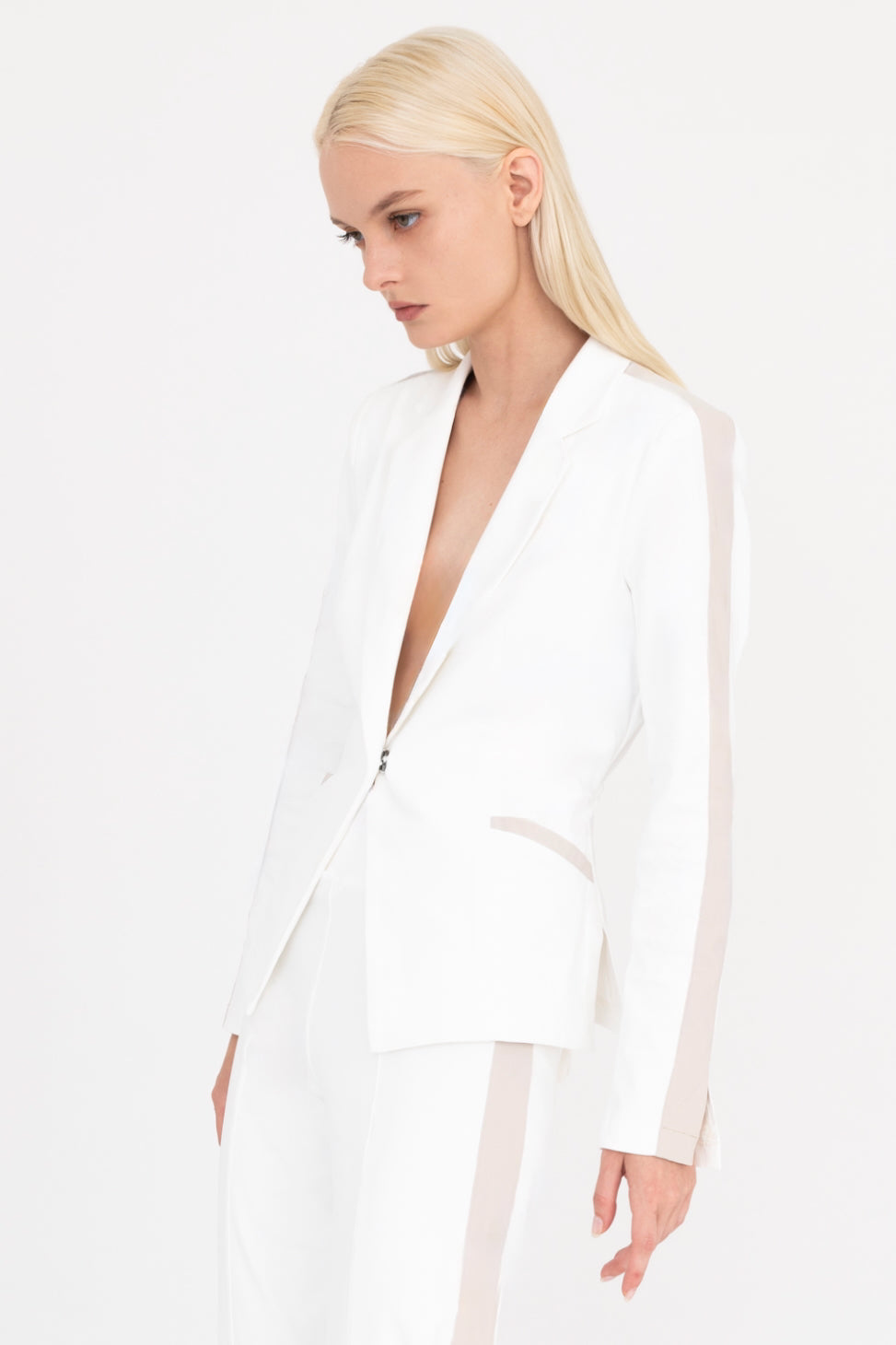 Woman wearing a white blazer with beige side stripe on a white background