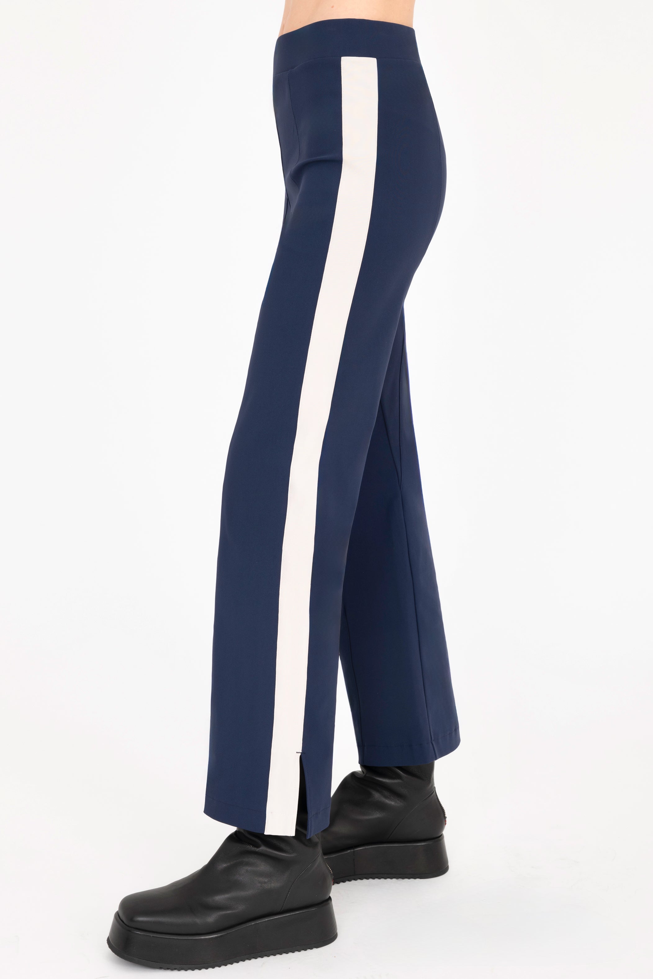 Side view of indigo blue cropped pants with beige side stripe on a white background
