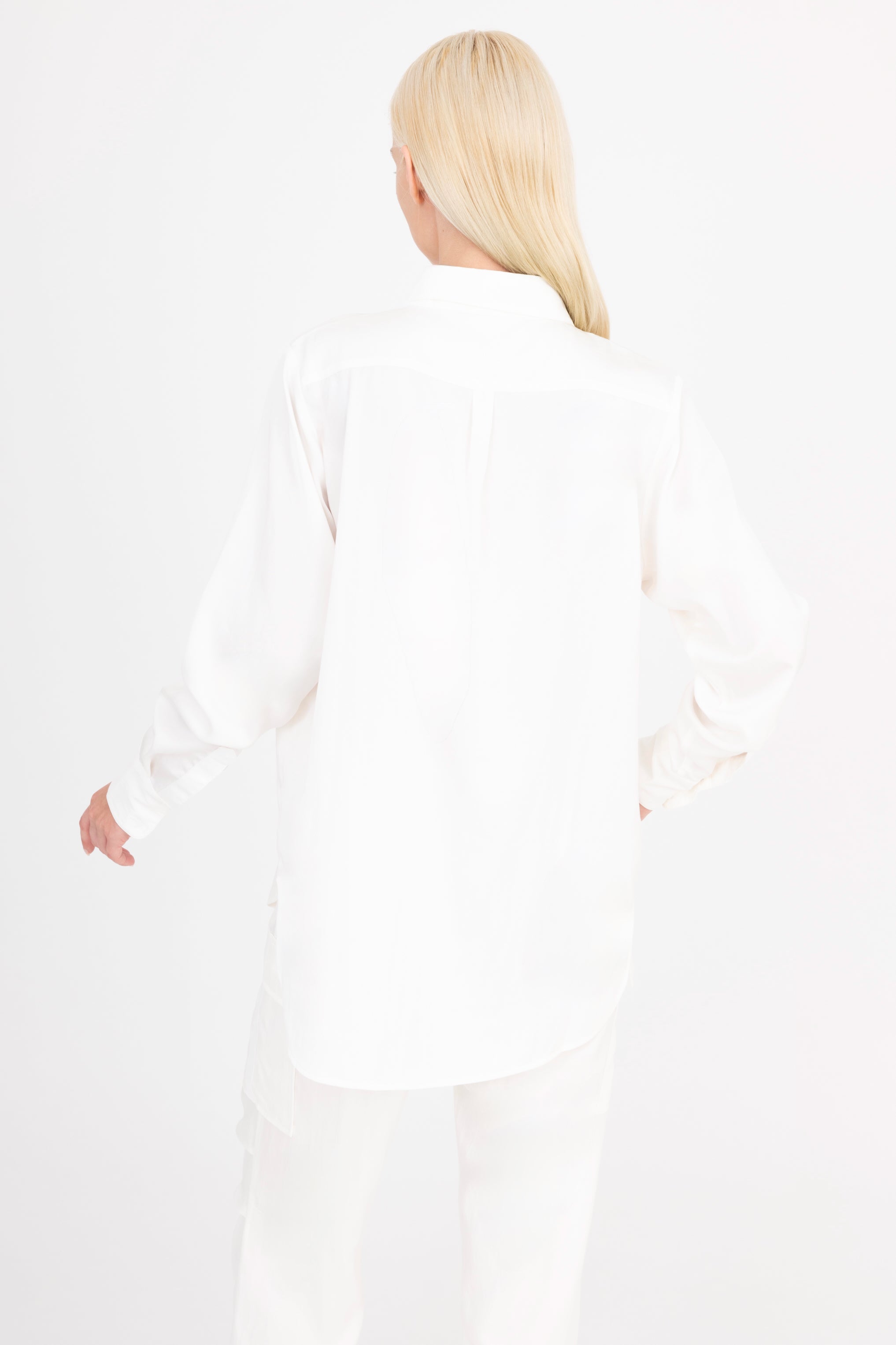 Back view of woman wearing a white shirt and pants on a white background