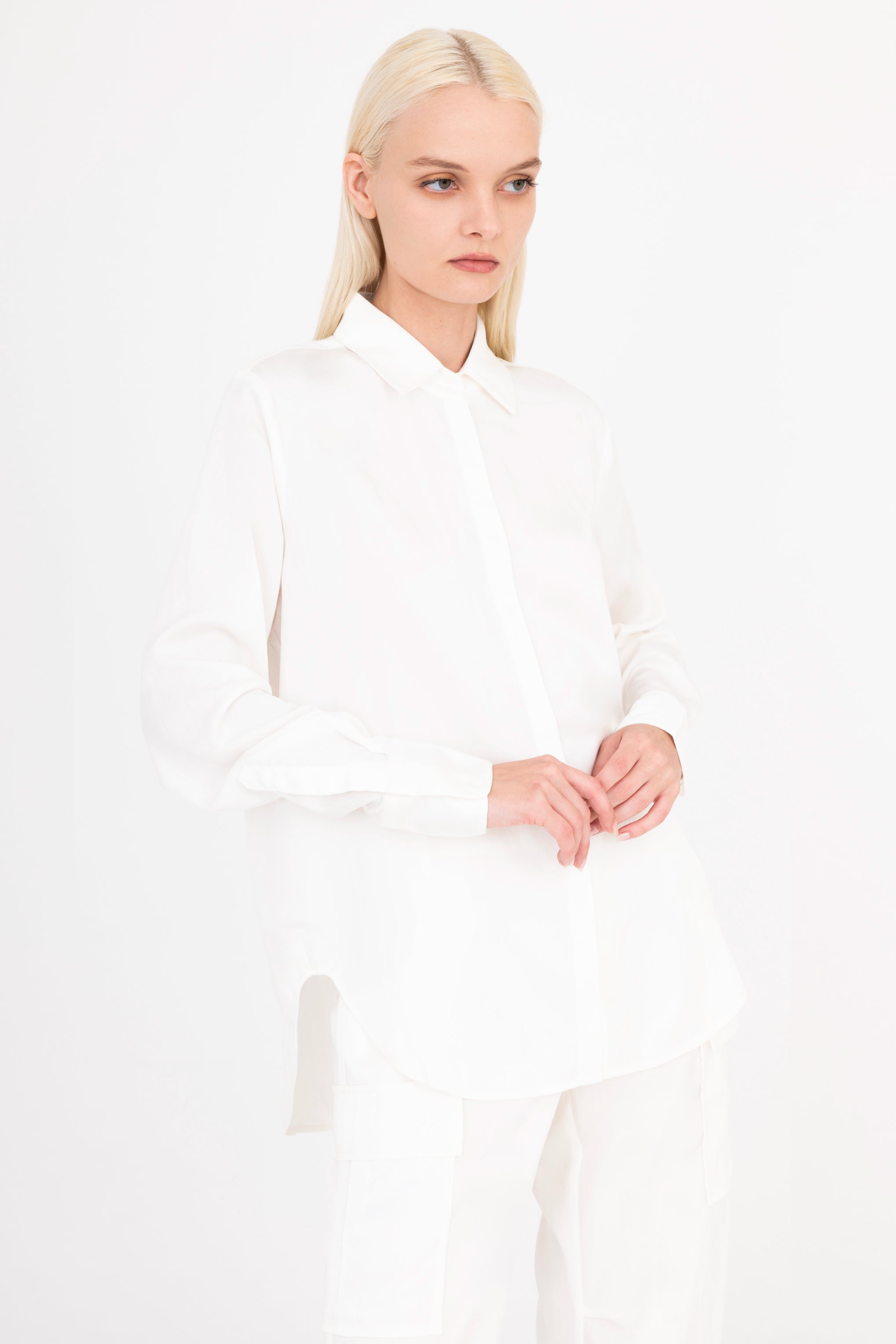 Quarter view of woman wearing a white shirt and pants on a white background