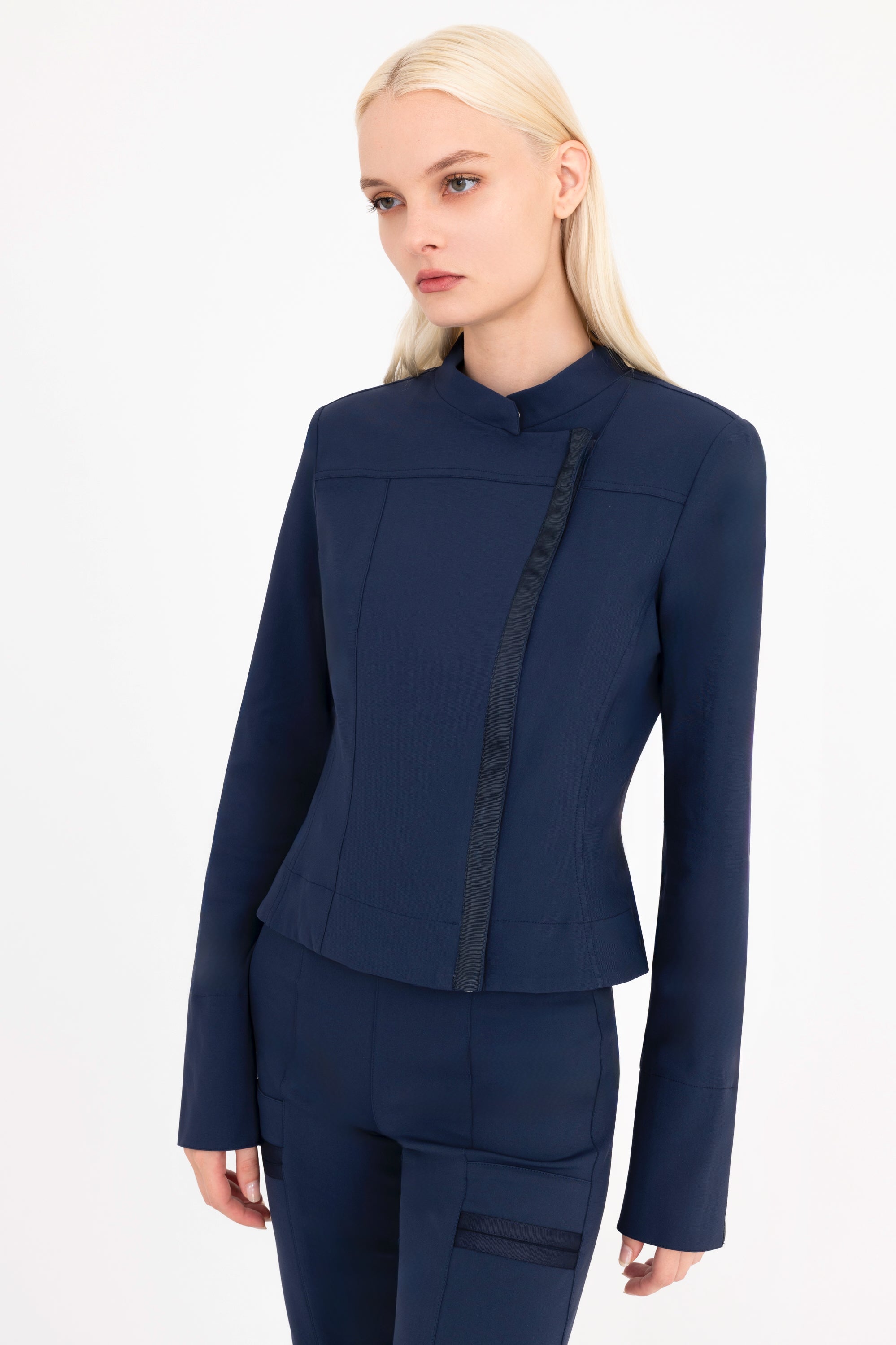 Woman wearing a navy moto jacket and pants  on a white background