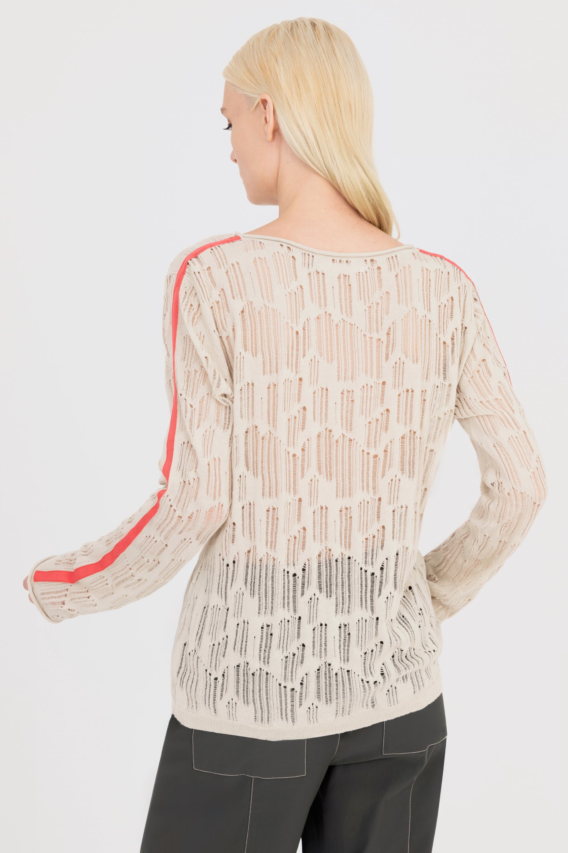 Woman wearing a beige sheer long-sleeve top with orange stripes on a white background
