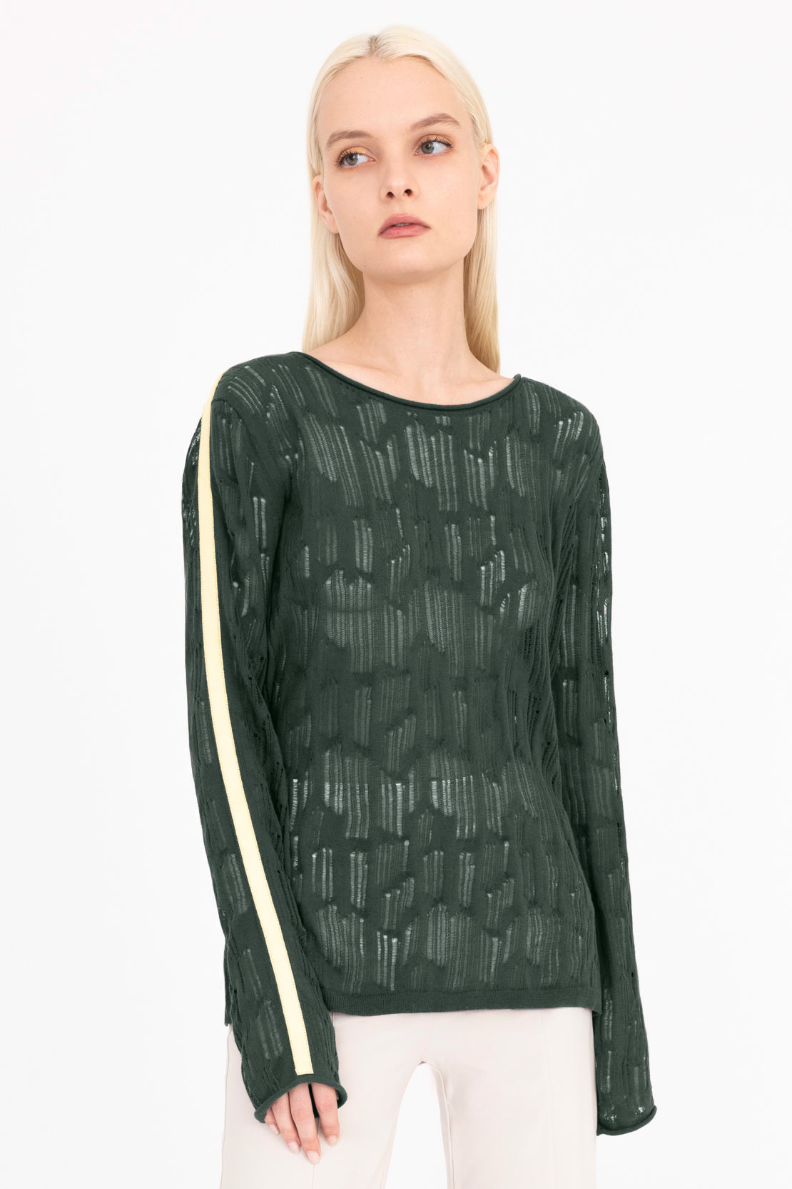Woman wearing a green sheer long-sleeve top with white stripes on a white background