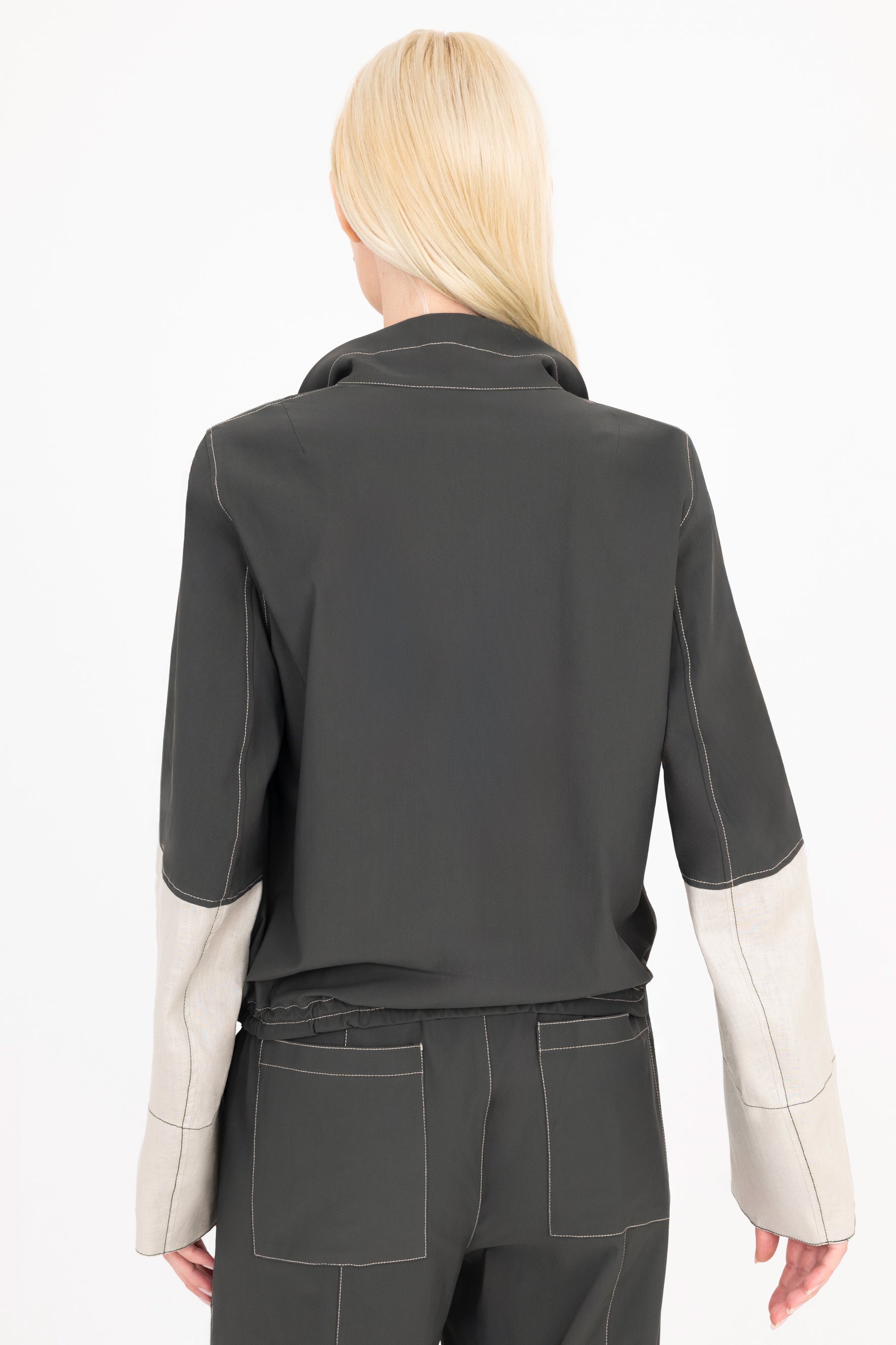 Woman wearing a pine green and beige jacket with a white background