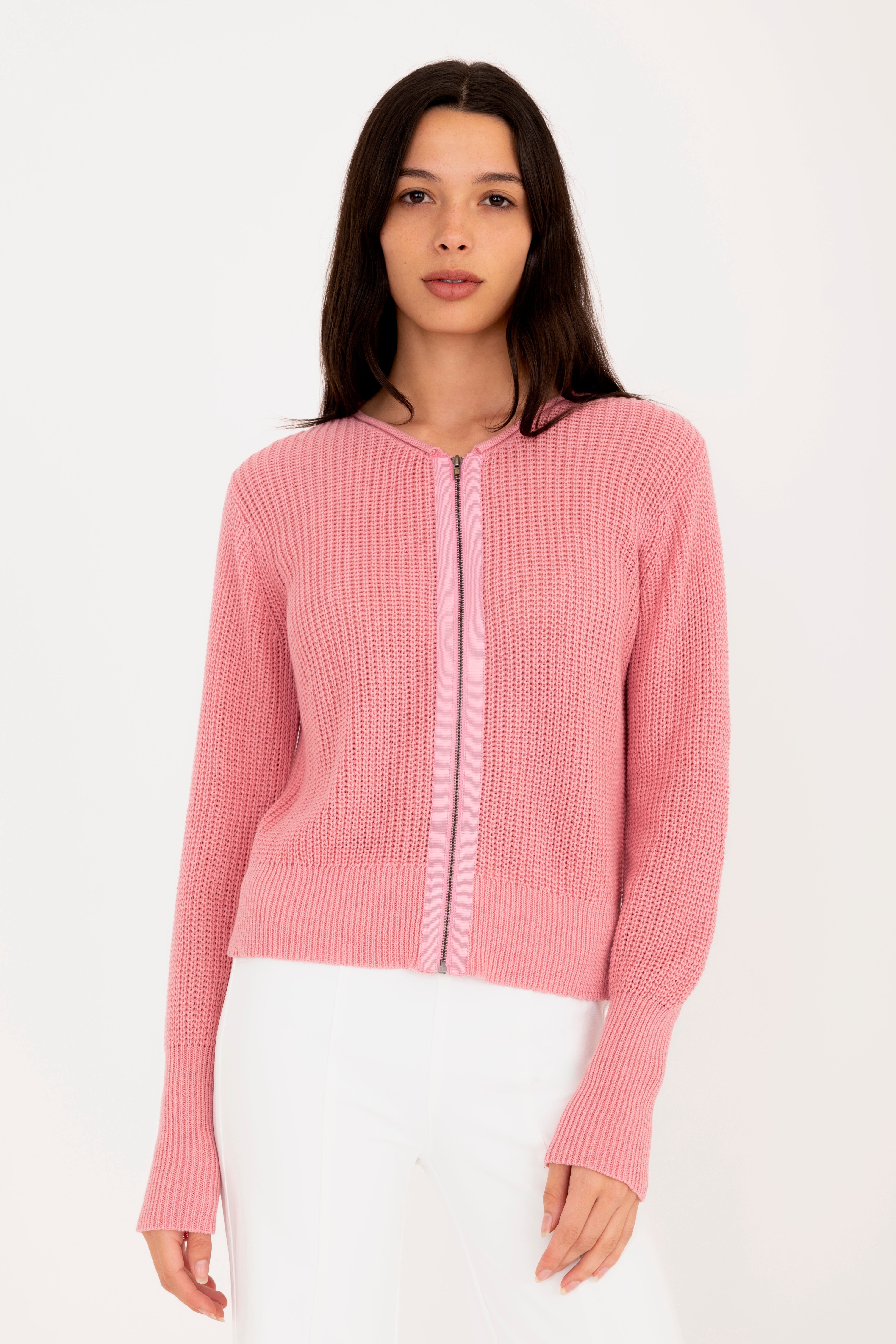 Woman wearing a pink zip-up sweater against a white background