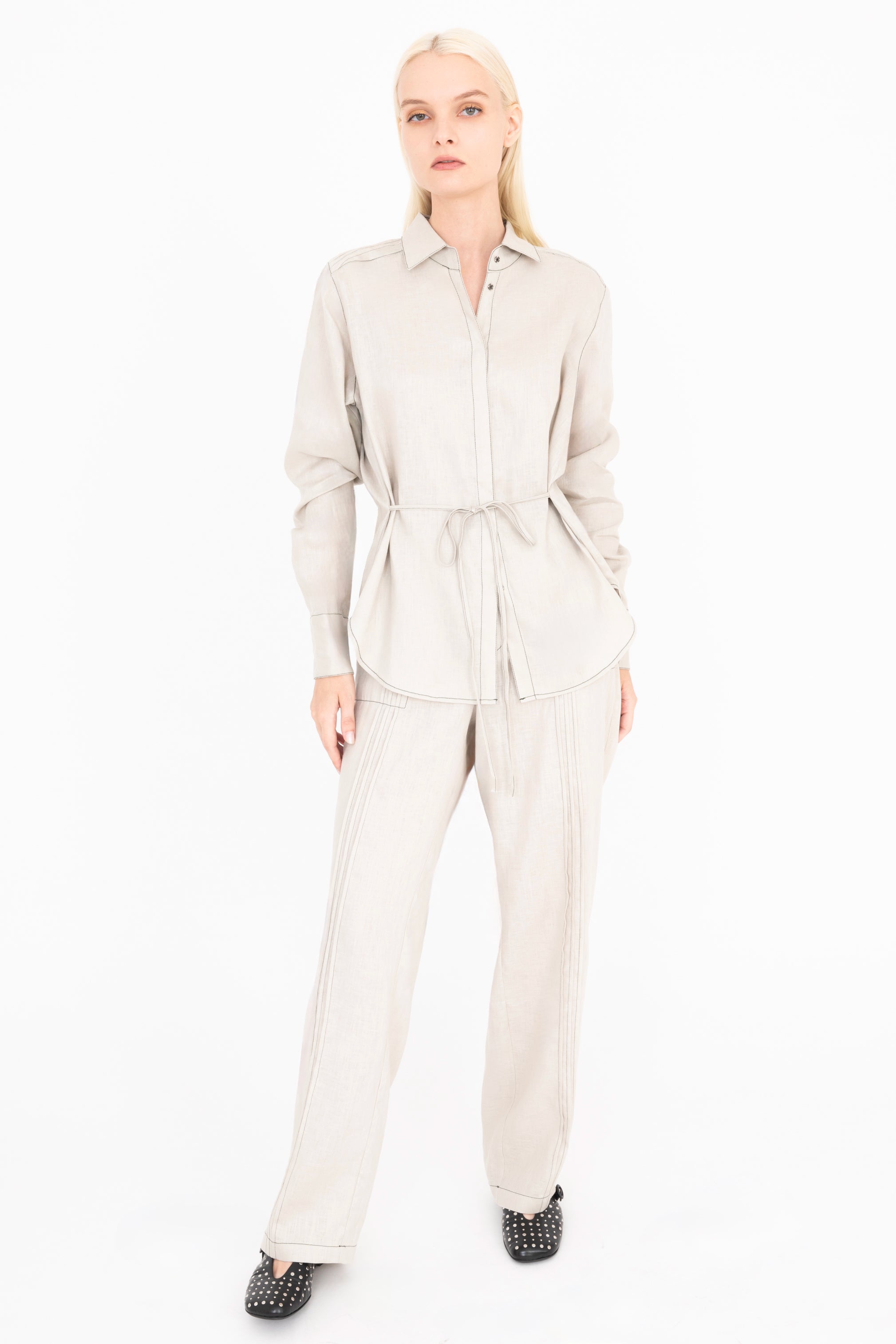 Woman wearing light beige shirt and pants on a white background