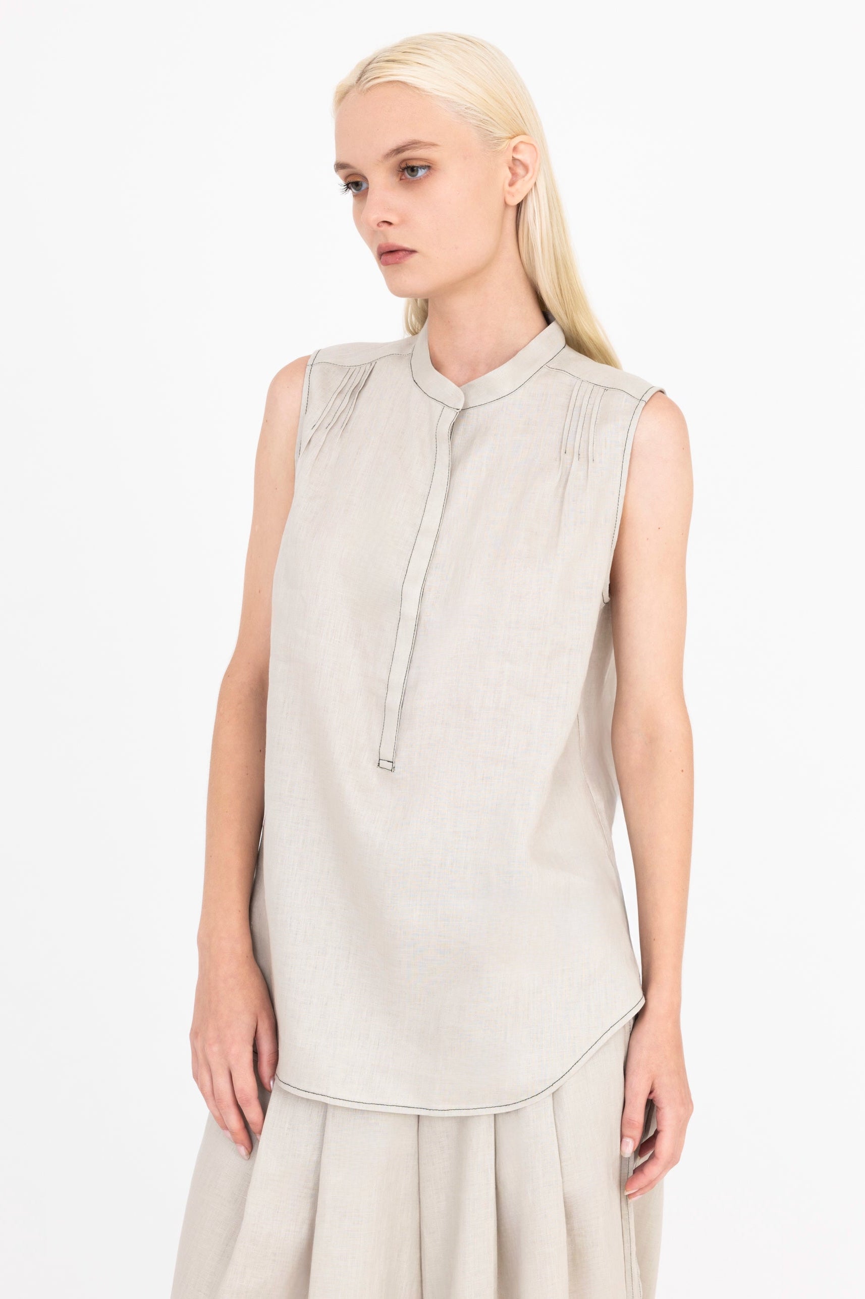 Woman wearing a light beige sleeveless top on a white background