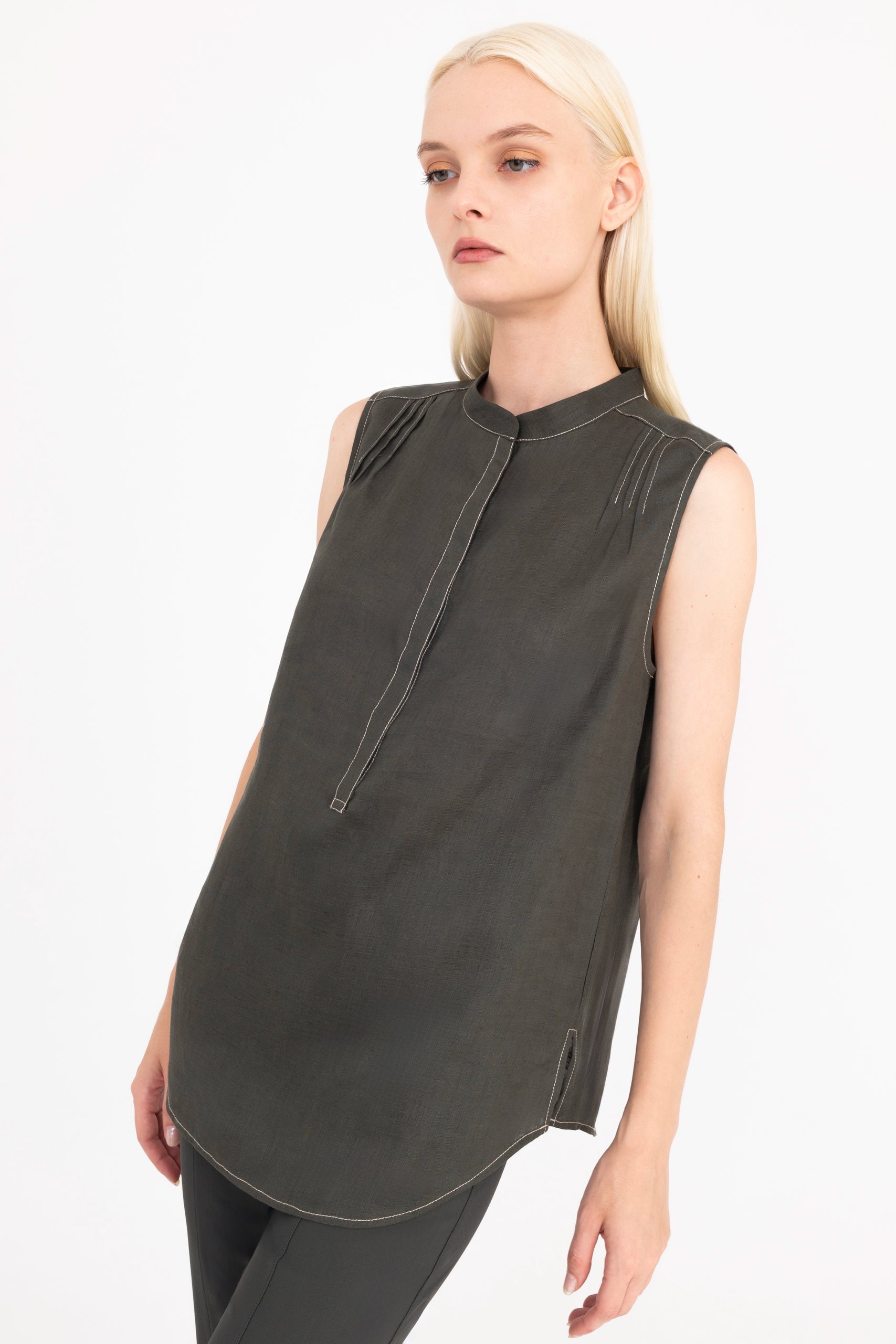Woman wearing a sleeveless pine green top on a white background